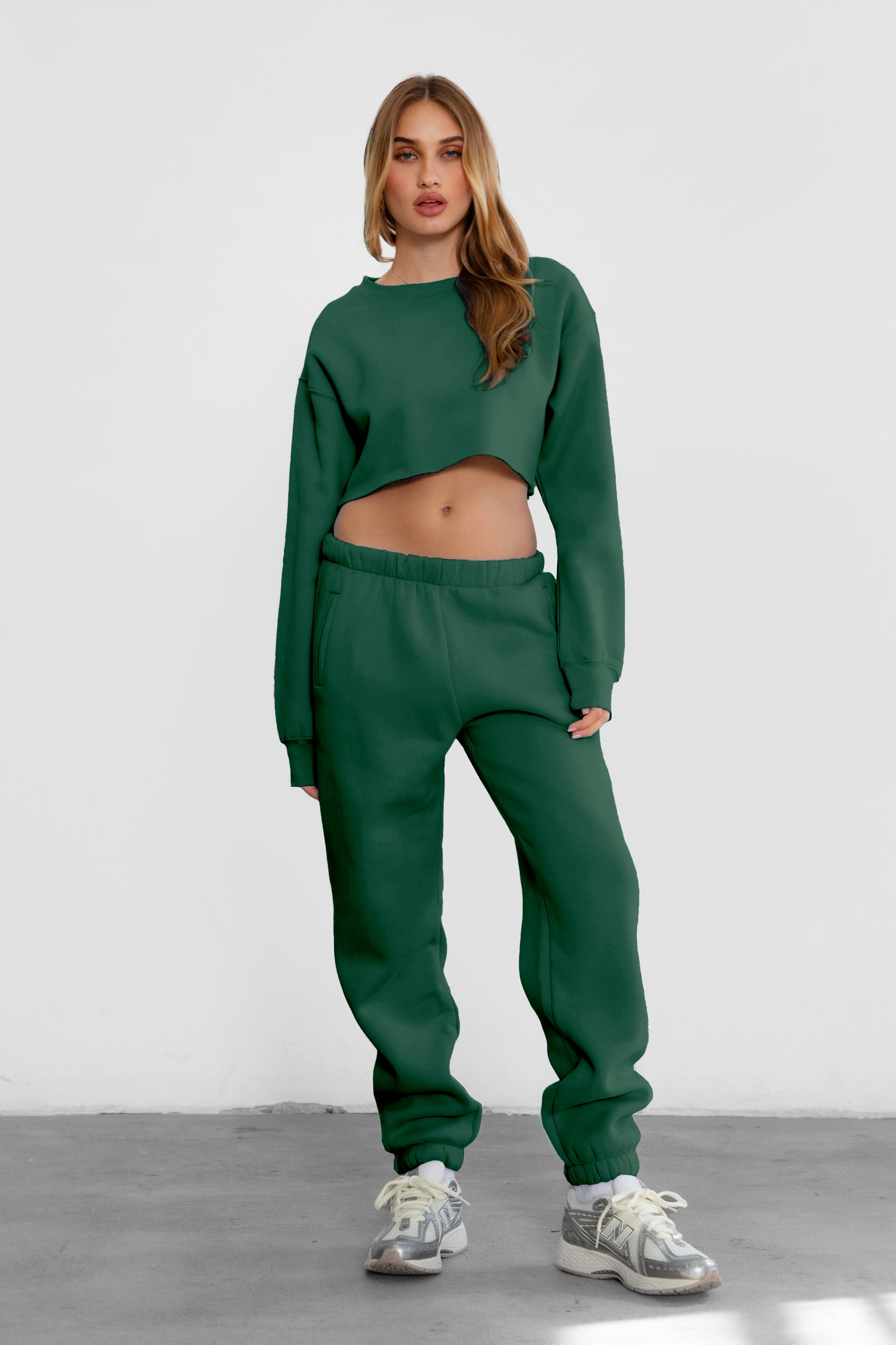 Woman wearing the TIC TOC PH26027 DOVE hunter green high waist sweatpants featuring an elastic waistband, deep side pockets, and tapered ankle hem with a matching top. 