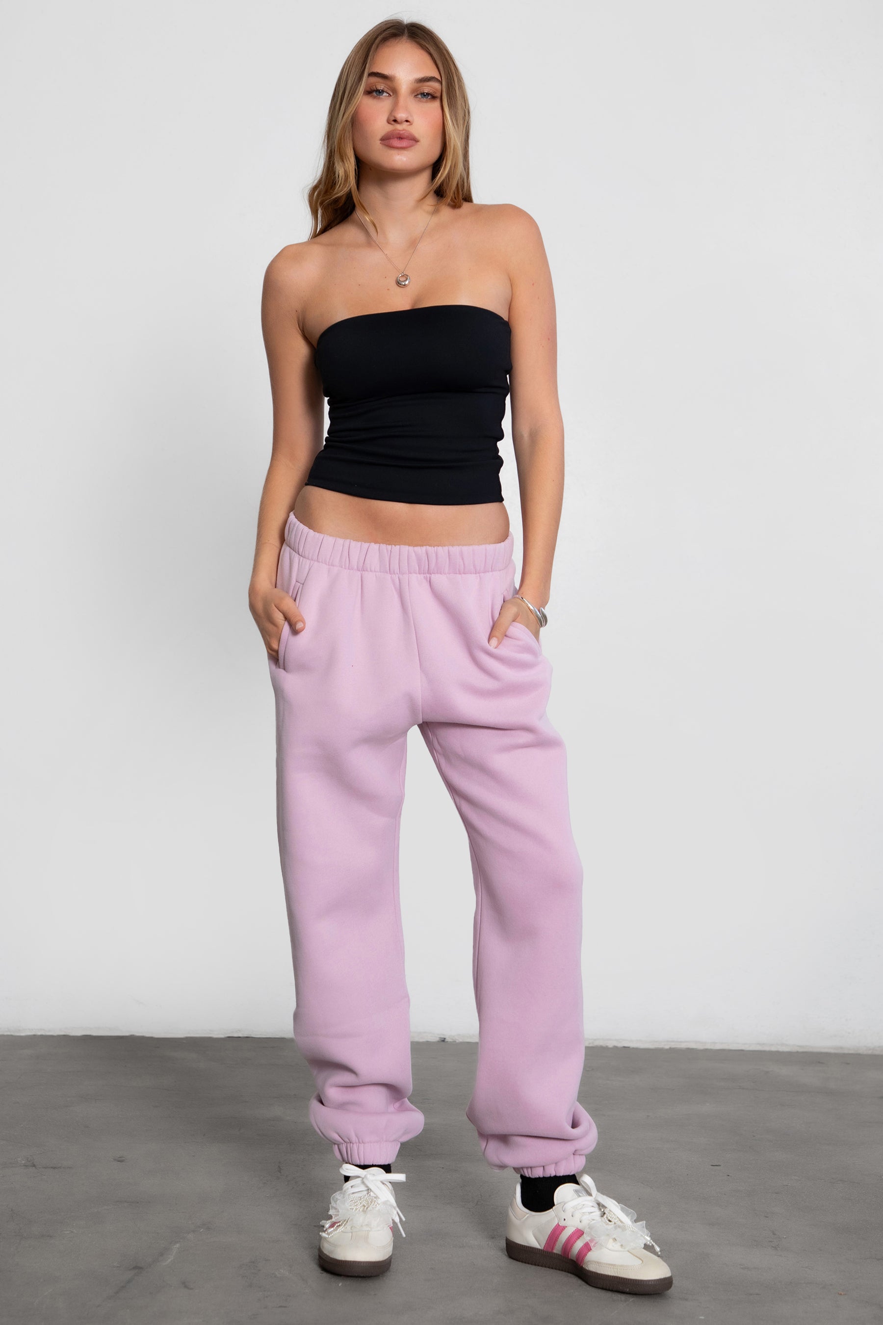 Woman wearing the TIC TOC PH26027 DOVE light lavender high waist sweatpants featuring an elastic waistband, deep side pockets, and tapered ankle hem with a matching top. 