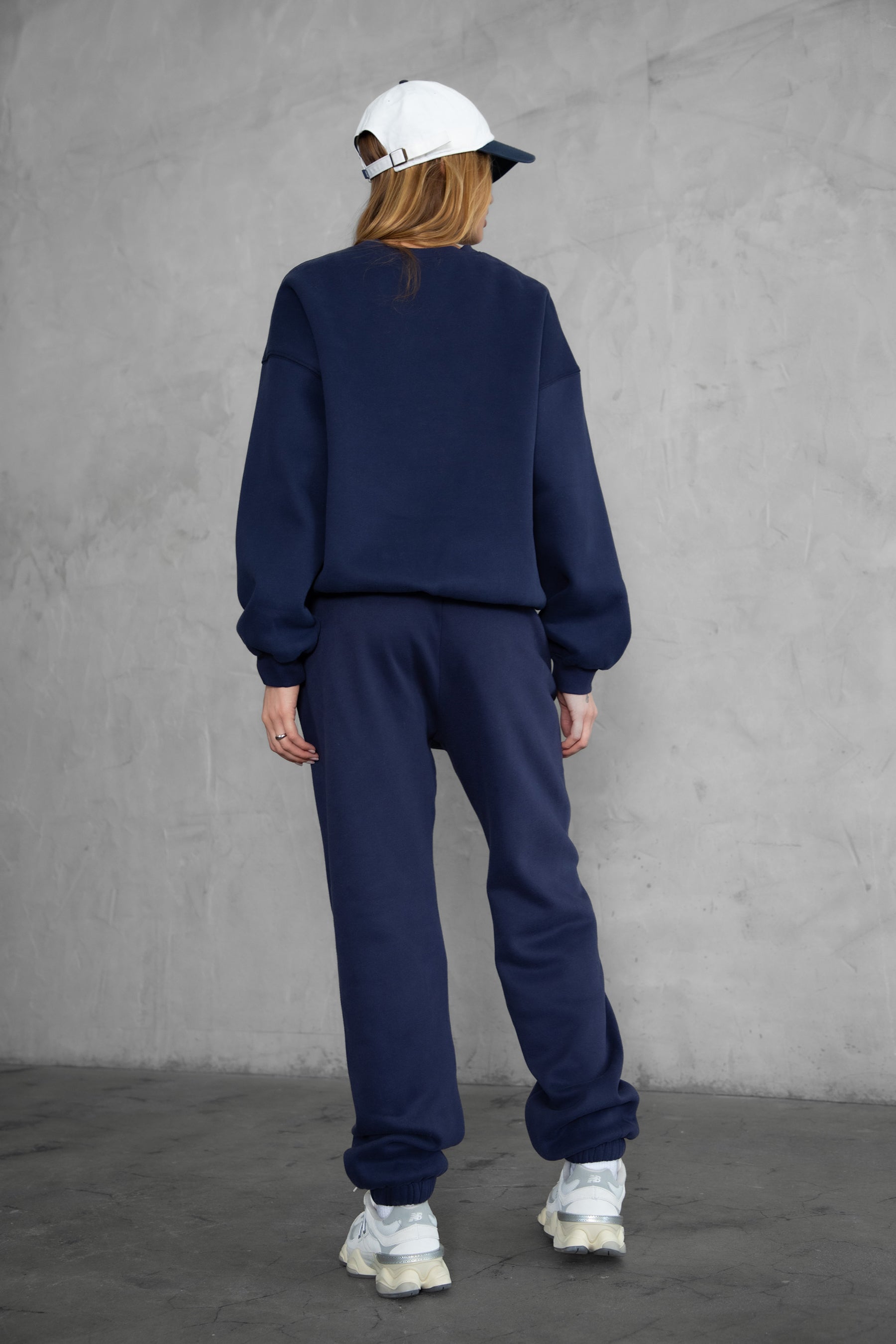 Woman wearing the TIC TOC PH26027 DOVE navy high waist sweatpants featuring an elastic waistband, deep side pockets, and tapered ankle hem with a matching top. 