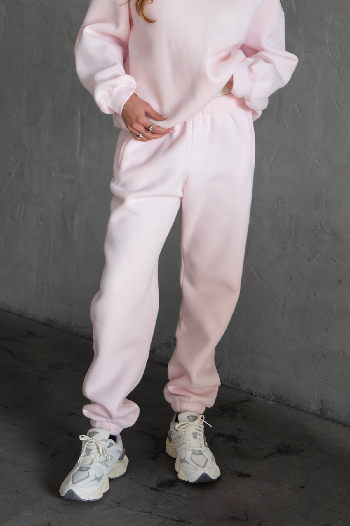 A pair of high-waisted, pink sweatpants with an elasticated waistband, side pockets, and an ankle-length fit.