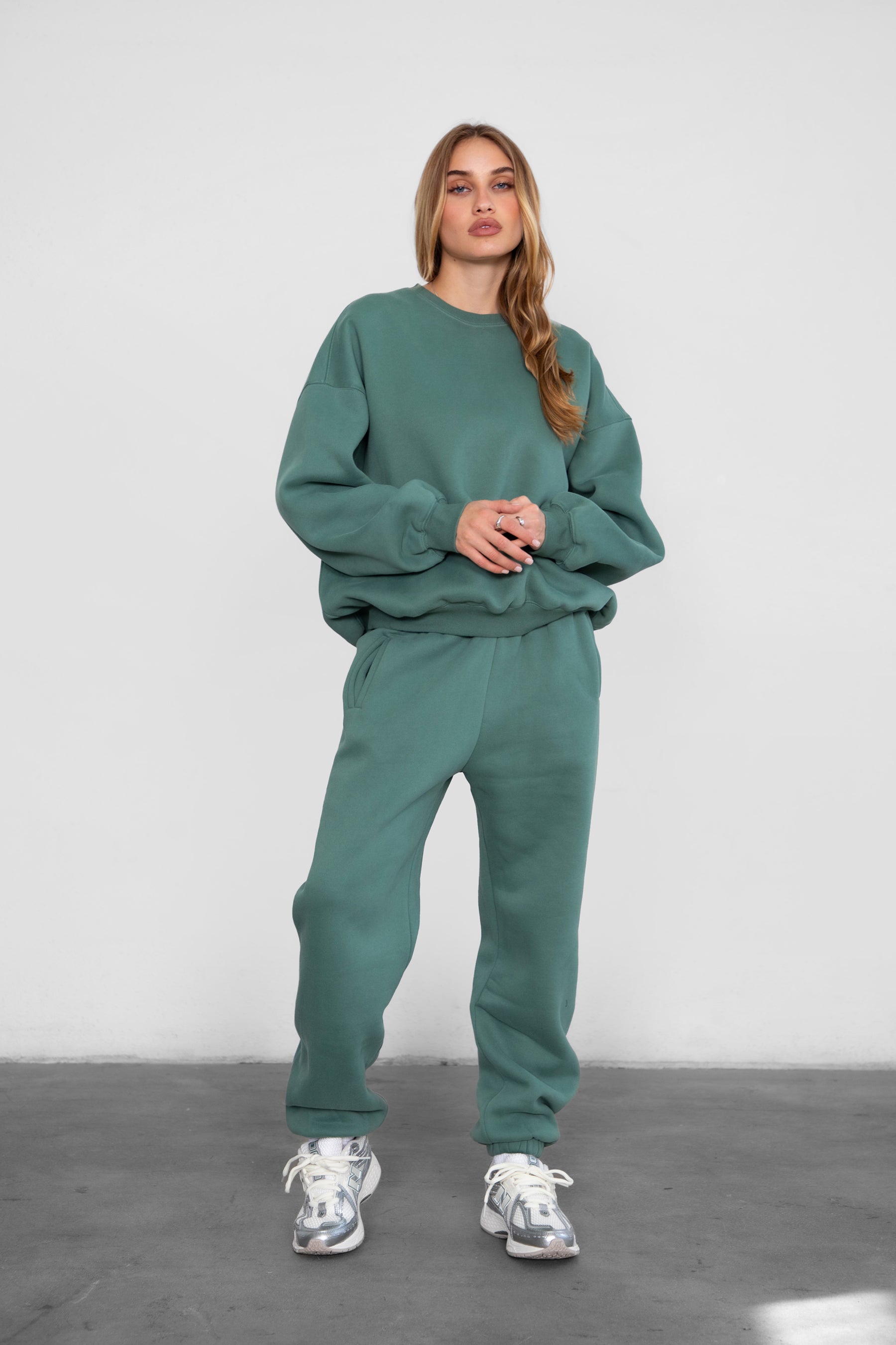 Woman wearing the TIC TOC PH26027 DOVE pine green high waist sweatpants featuring an elastic waistband, deep side pockets, and tapered ankle hem with a matching top. 