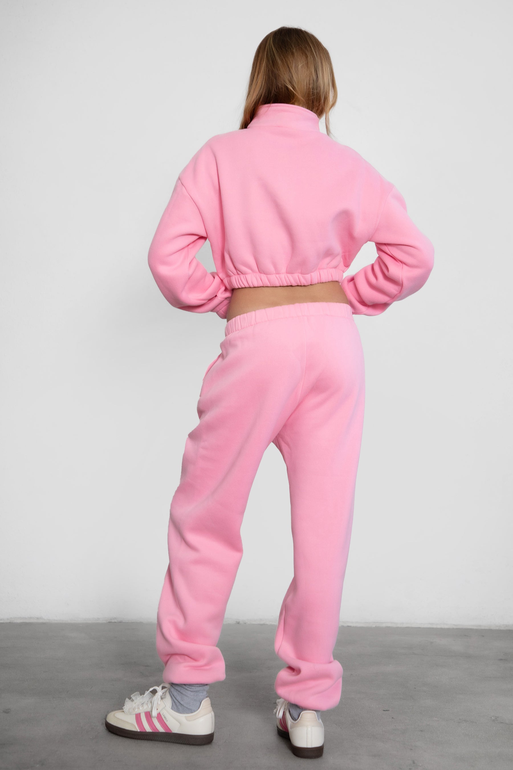 Woman wearing the TIC TOC PH26027 DOVE pink high waist sweatpants featuring an elastic waistband, deep side pockets, and tapered ankle hem with a matching top. 