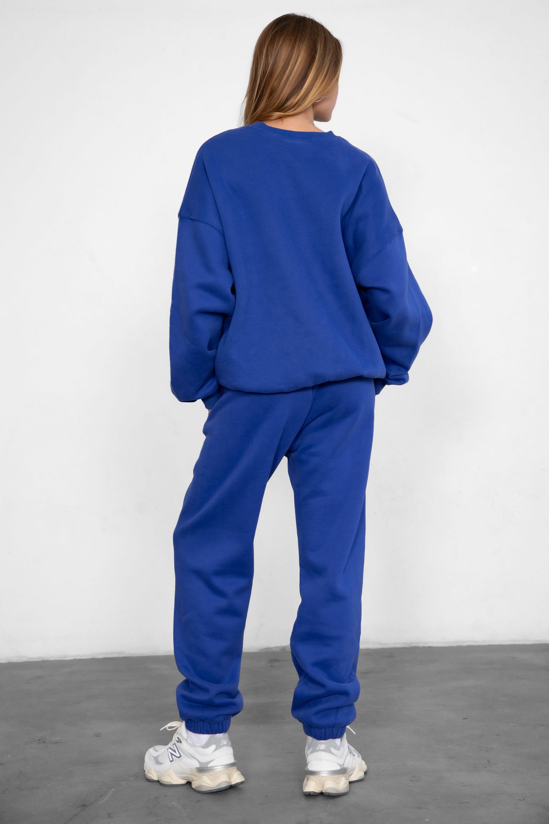 Woman wearing the TIC TOC PH26027 DOVE royal blue high waist sweatpants featuring an elastic waistband, deep side pockets, and tapered ankle hem with a matching top. 