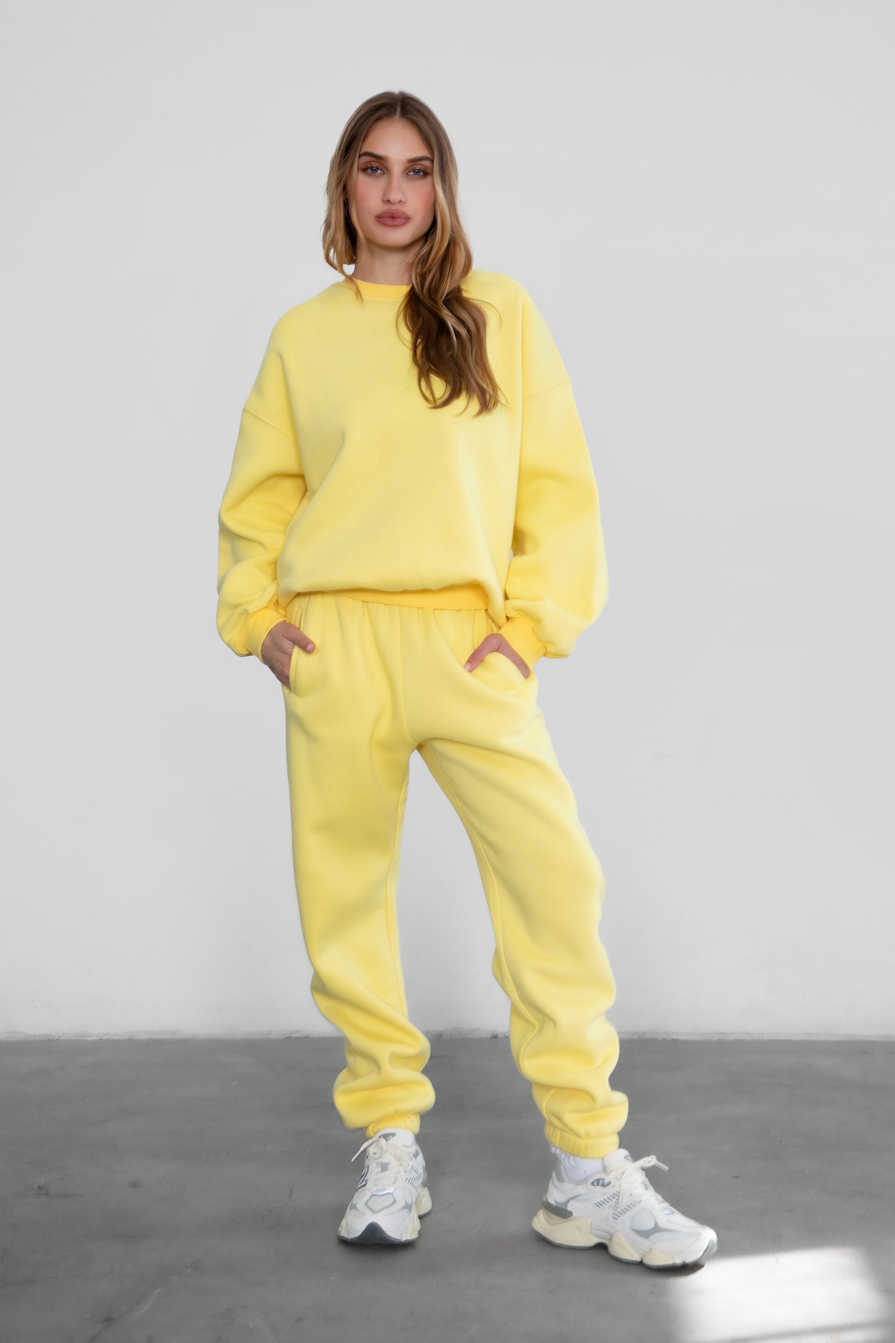Woman wearing the TIC TOC PH26027 DOVE yellow high waist sweatpants featuring an elastic waistband, deep side pockets, and tapered ankle hem with a matching top. 