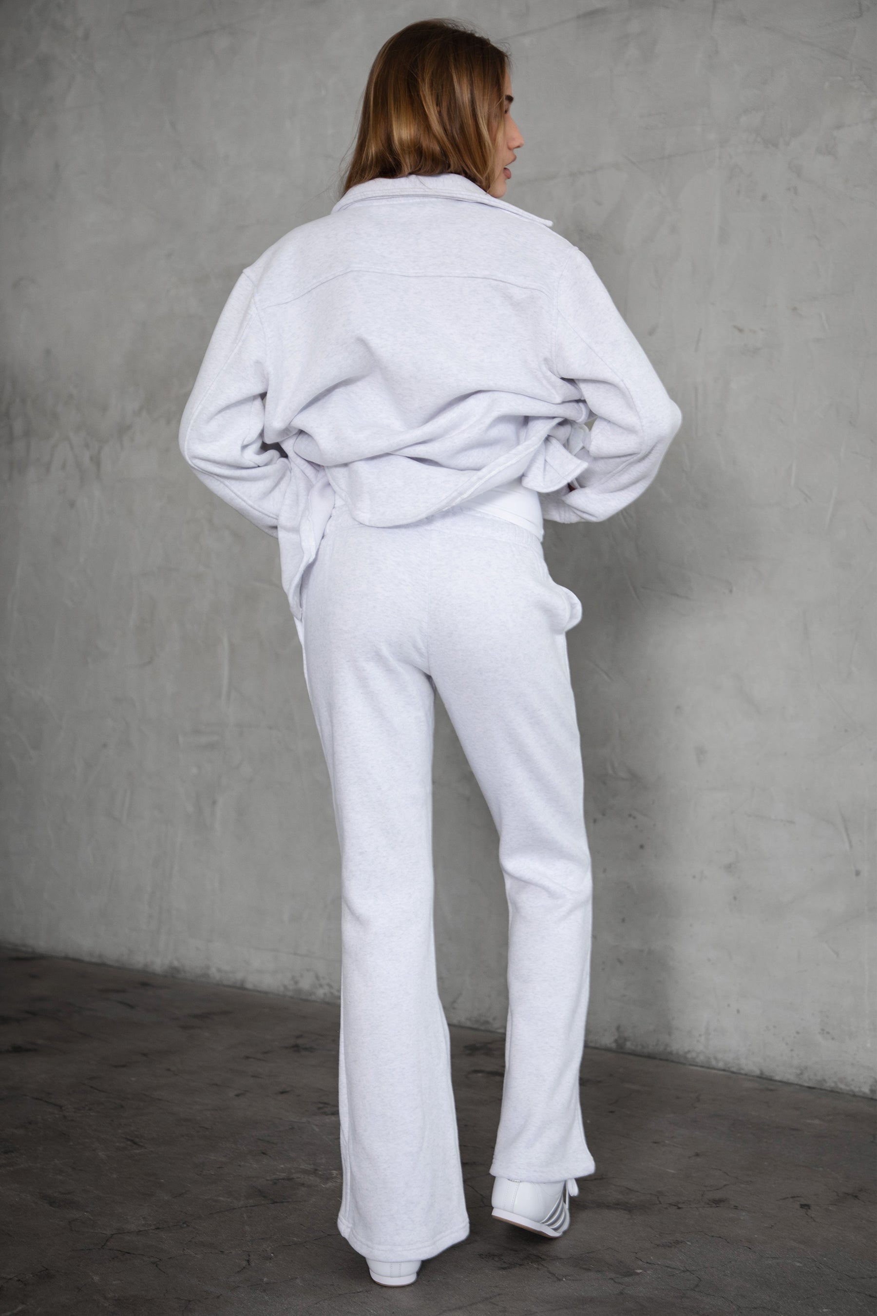 Woman wearing TIC TOC PH29142 JIYA essential fleece flare sweatpants with mid-rise waistband and side pockets from plush fleece collection  in heather white paired with a matching jacket. 