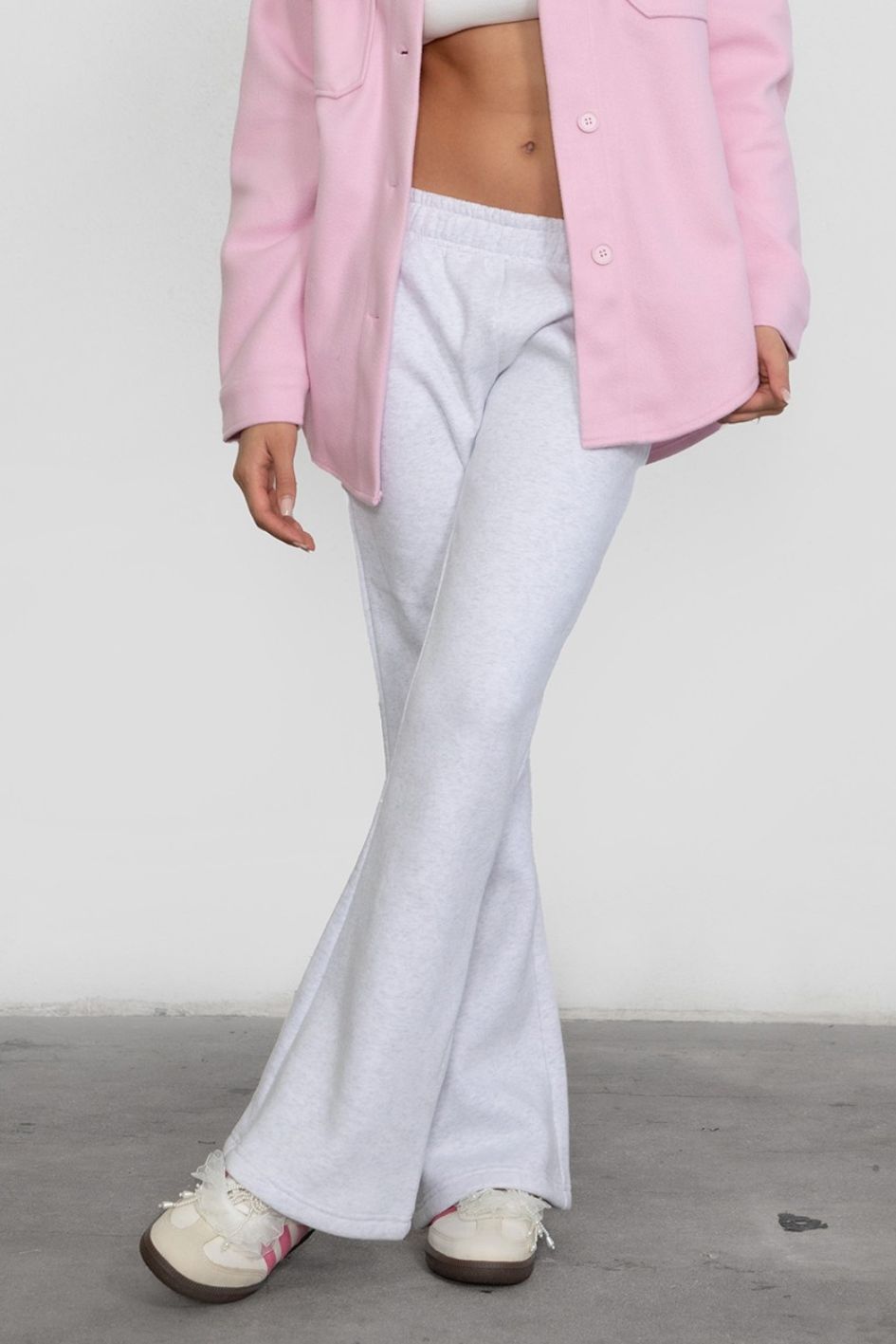 Person wearing a pink jacket and light heather white pants on a plain background
