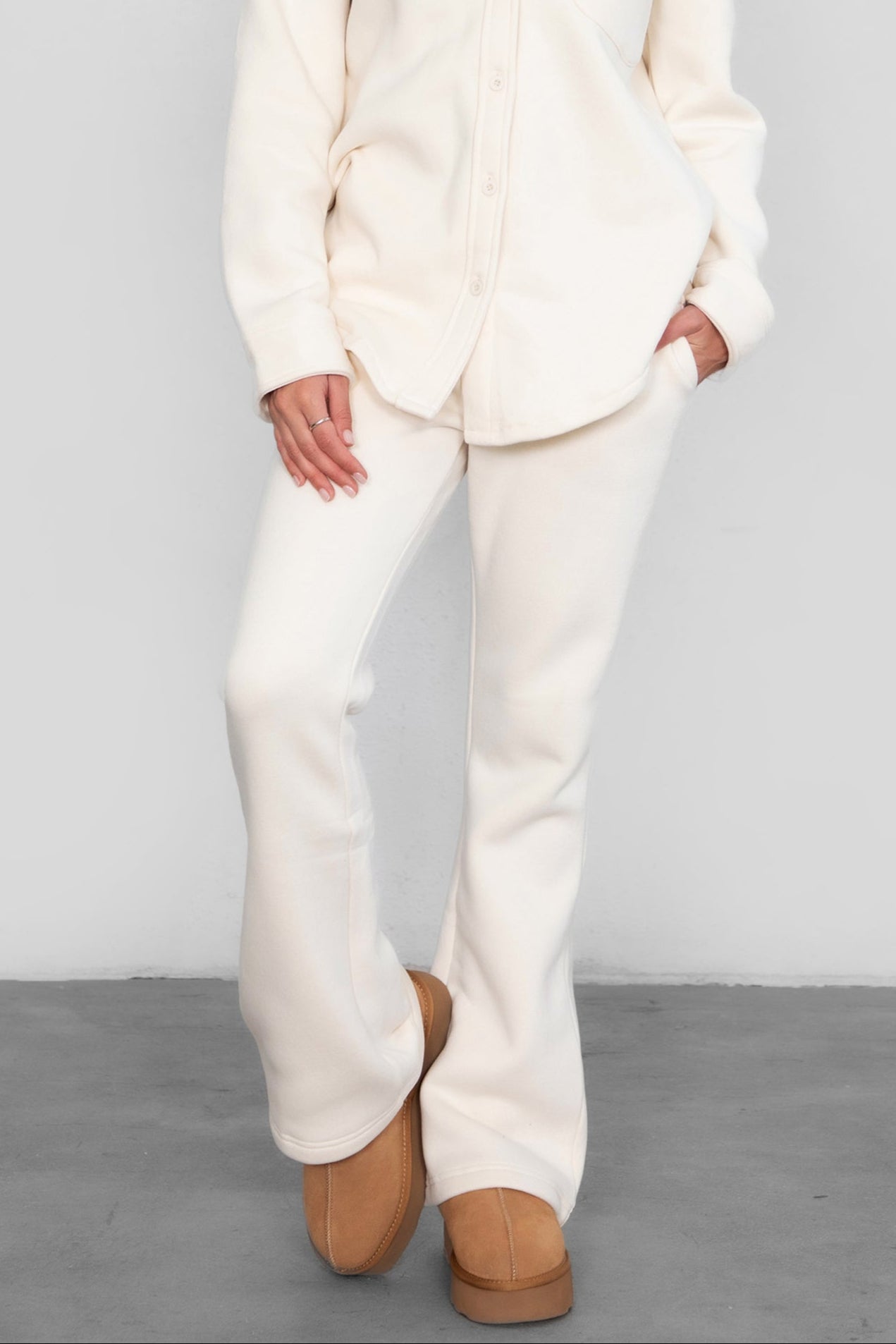Woman wearing TIC TOC PH29142 JIYA essential fleece flare sweatpants with mid-rise waistband and side pockets from plush fleece collection  in ecru paired with a matching shacket.