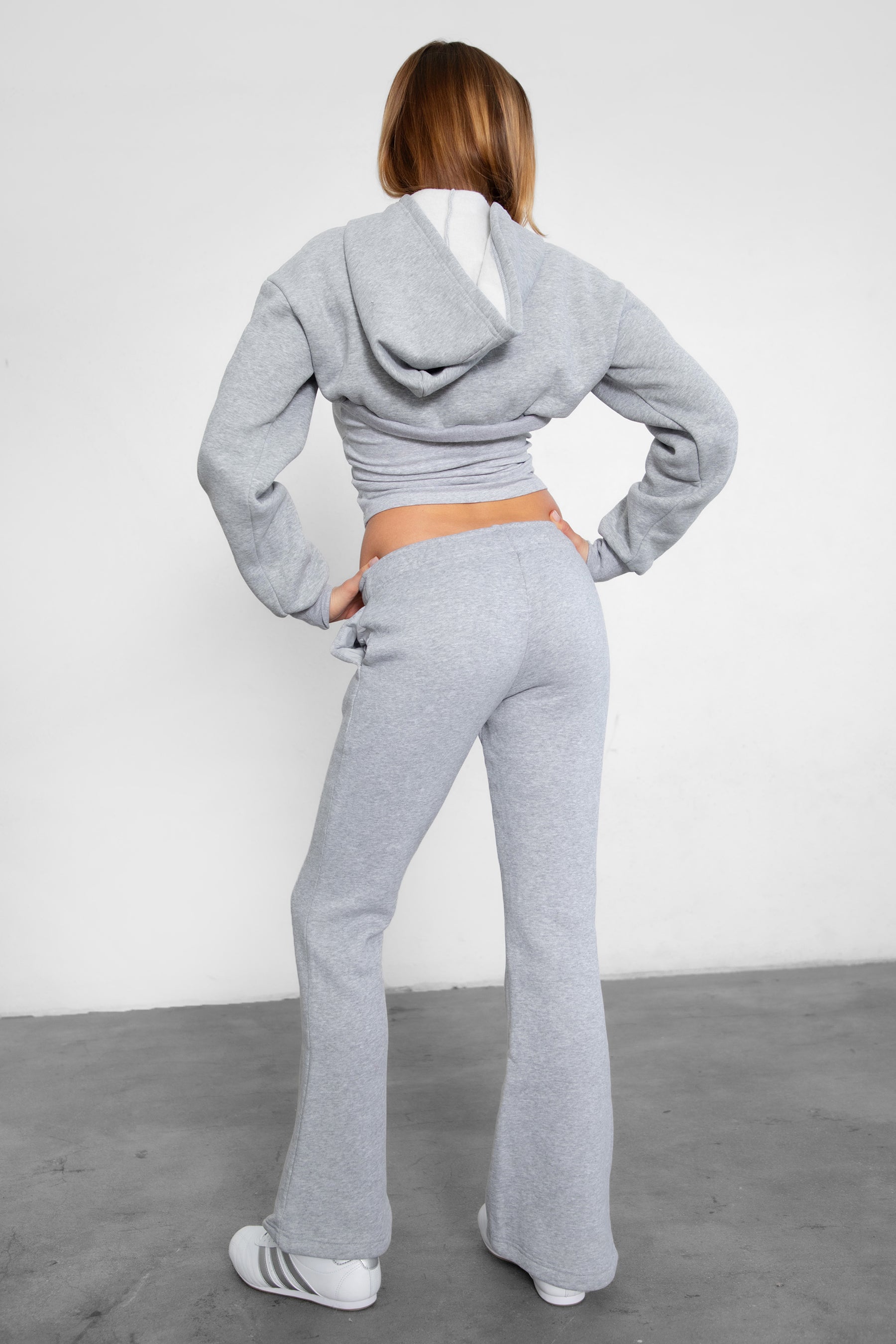 Woman wearing TIC TOC PH29142 JIYA essential fleece flare sweatpants with mid-rise waistband and side pockets from plush fleece collection  in heather grey paired with a matching top and bolero. 