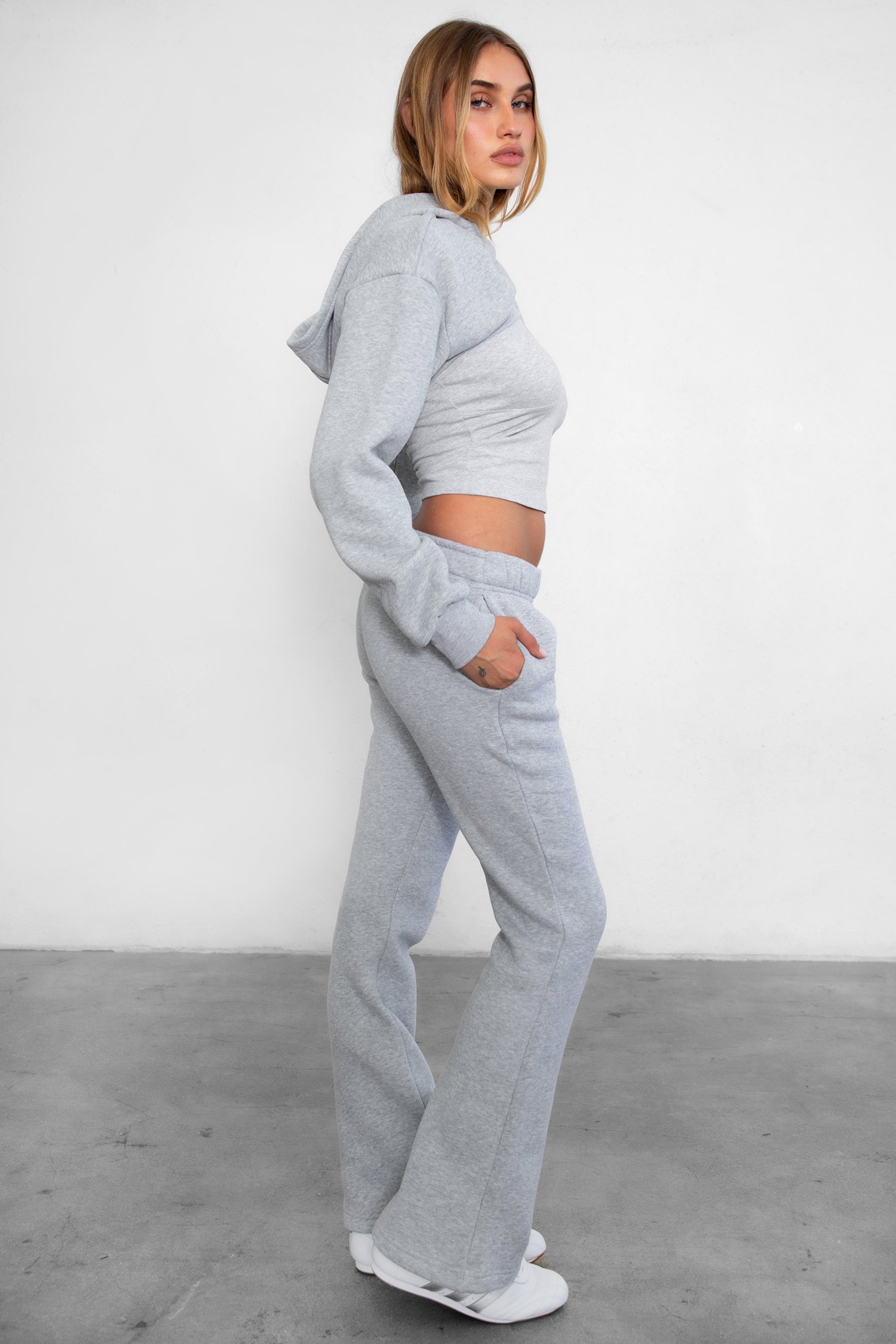 Woman wearing TIC TOC PH29142 JIYA essential fleece flare sweatpants with mid-rise waistband and side pockets from plush fleece collection  in heather grey paired with a matching top and bolero. 
