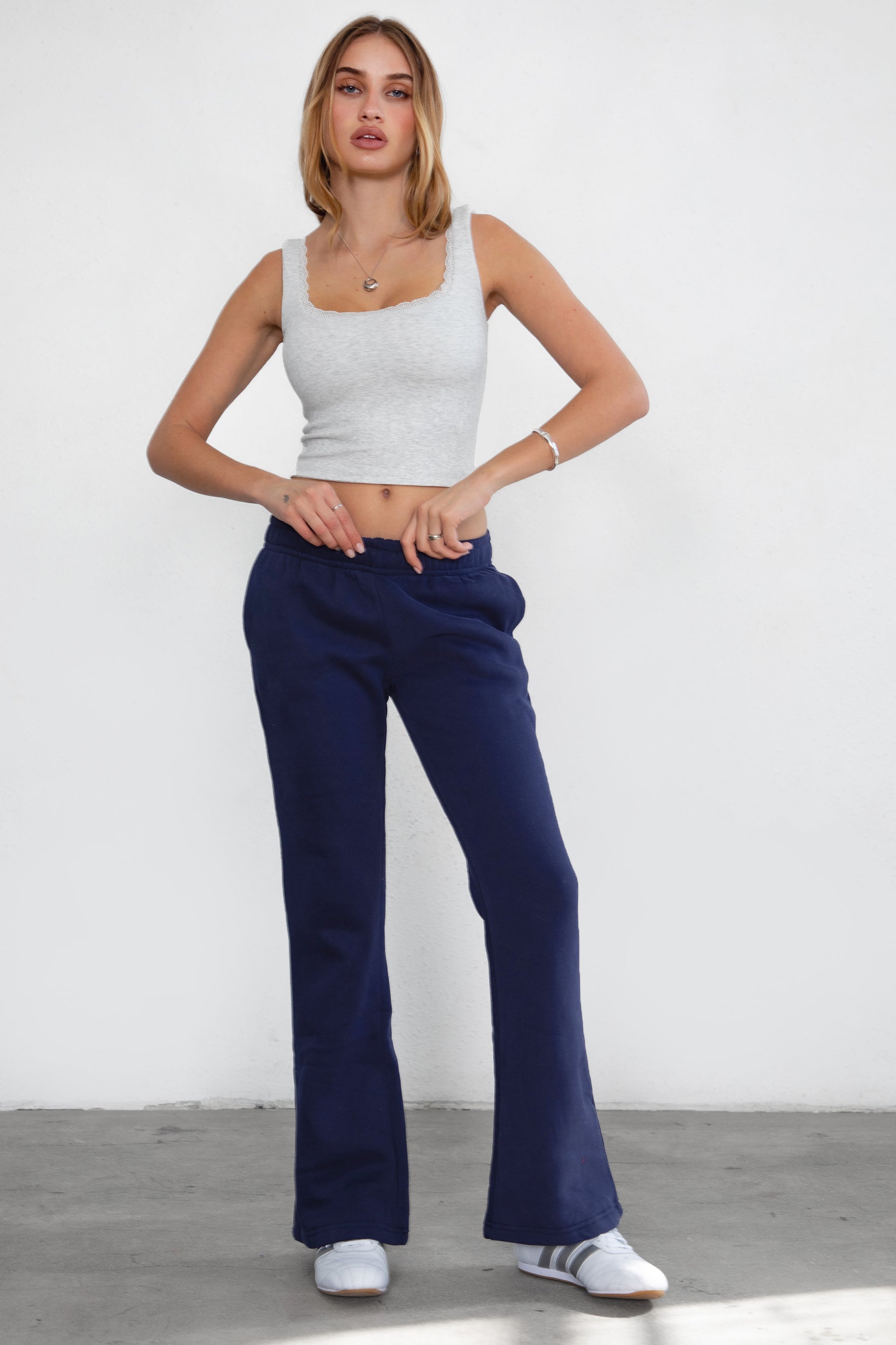 Woman wearing TIC TOC PH29142 JIYA essential fleece flare sweatpants with mid-rise waistband and side pockets from plush fleece collection  in navy paired with a heather white top. 