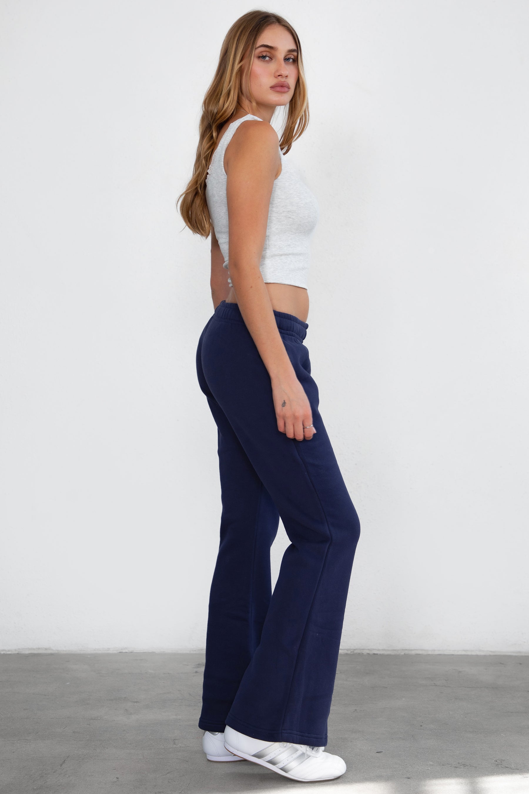 Woman wearing TIC TOC PH29142 JIYA essential fleece flare sweatpants with mid-rise waistband and side pockets from plush fleece collection  in navy paired with a heather white top. 
