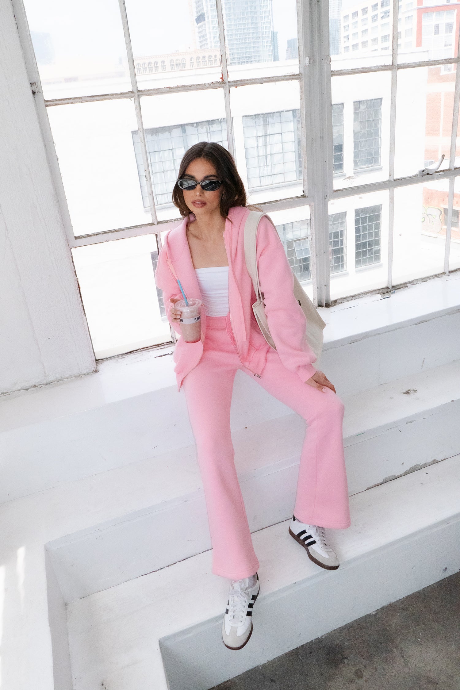 Woman wearing TIC TOC PH29142 JIYA essential fleece flare sweatpants with mid-rise waistband and side pockets from plush fleece collection  in blush paired with a white bandeau top and matching jacket