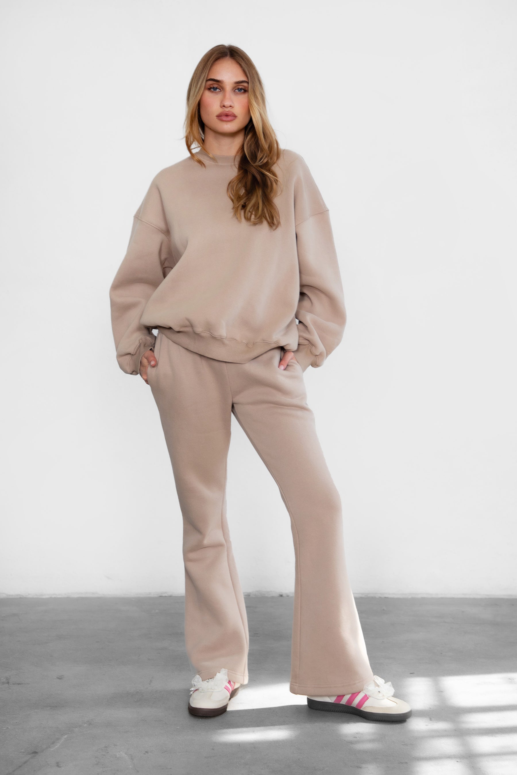 Woman wearing TIC TOC PH29142 JIYA essential fleece flare sweatpants with mid-rise waistband and side pockets from plush fleece collection  in taupe paired with a matching crew neck