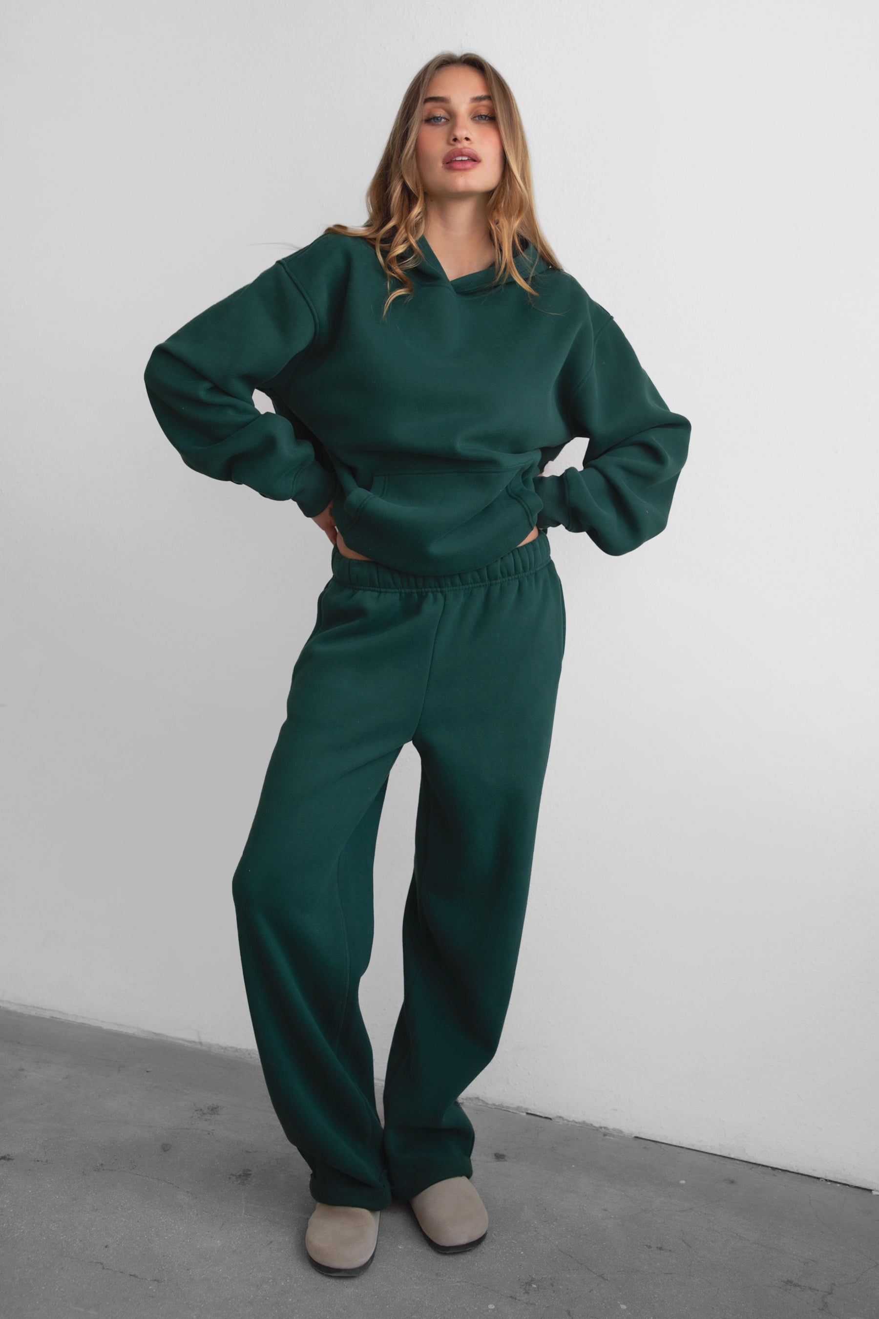 Woman wearing the TIC TOC PJ30241 LANI forrest green cloud fleece wide leg sweatpants featuring a straight leg silhouette, drawcord waistband, and side pockets paired with a matching hoodie. 