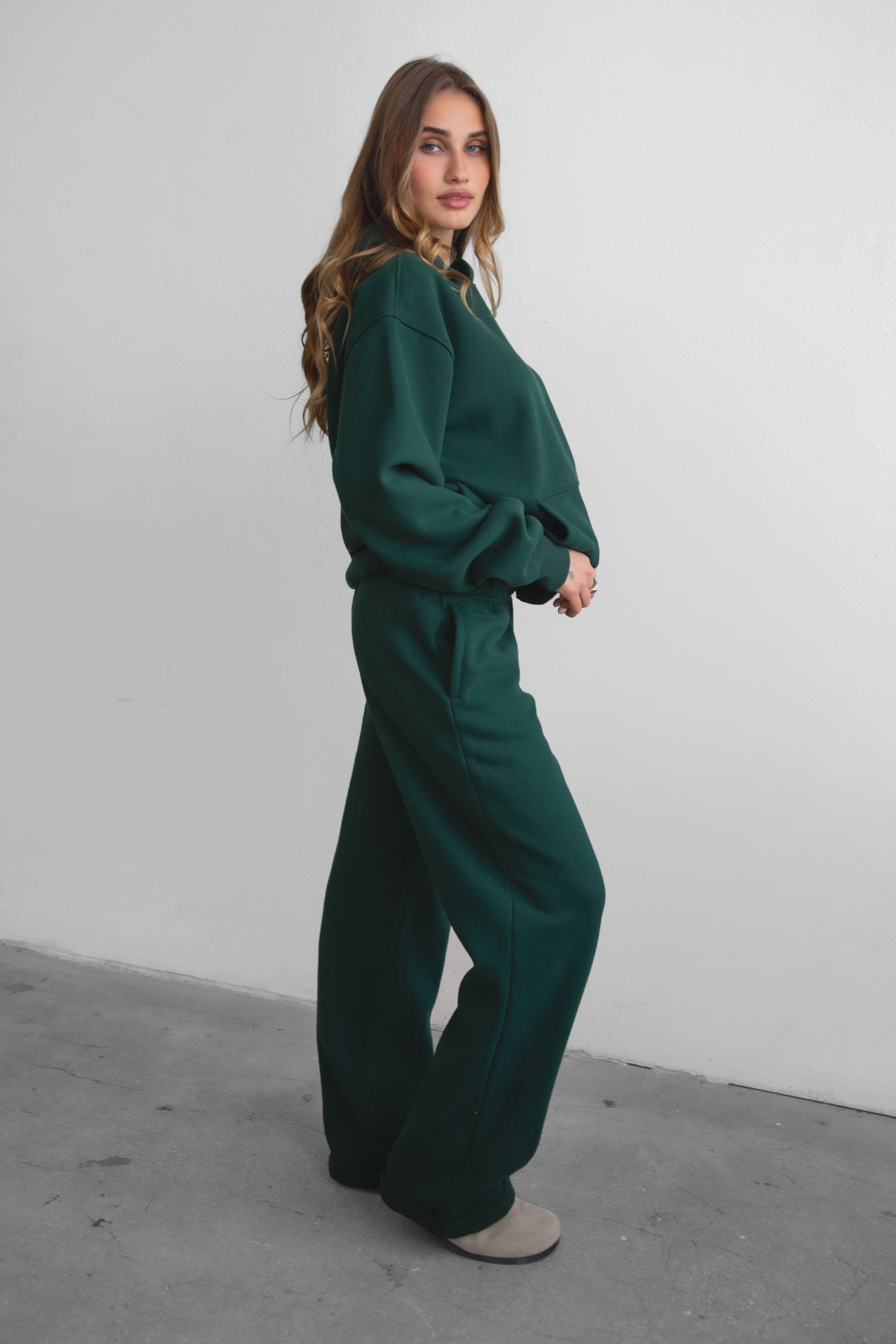 Woman wearing the TIC TOC PJ30241 LANI forrest green cloud fleece wide leg sweatpants featuring a straight leg silhouette, drawcord waistband, and side pockets paired with a matching hoodie. 