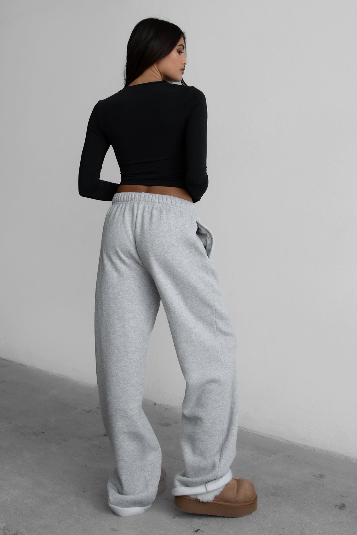 Woman wearing the TIC TOC PJ30241 LANI heather grey cloud fleece wide leg sweatpants featuring a straight leg silhouette, drawcord waistband, and side pockets paired with a black top. 