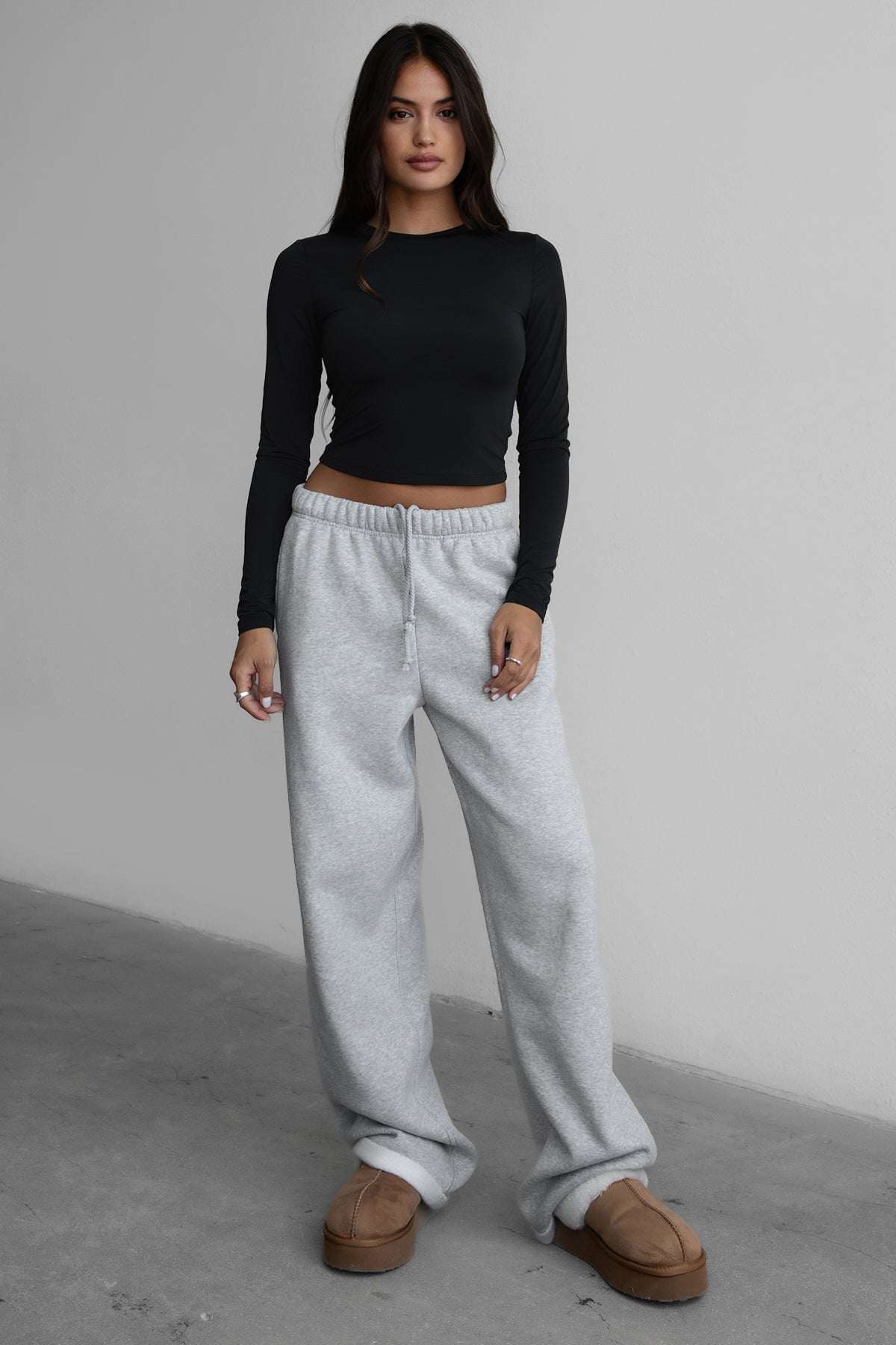 Woman wearing the TIC TOC PJ30241 LANI heather grey cloud fleece wide leg sweatpants featuring a straight leg silhouette, drawcord waistband, and side pockets paired with a black top. 