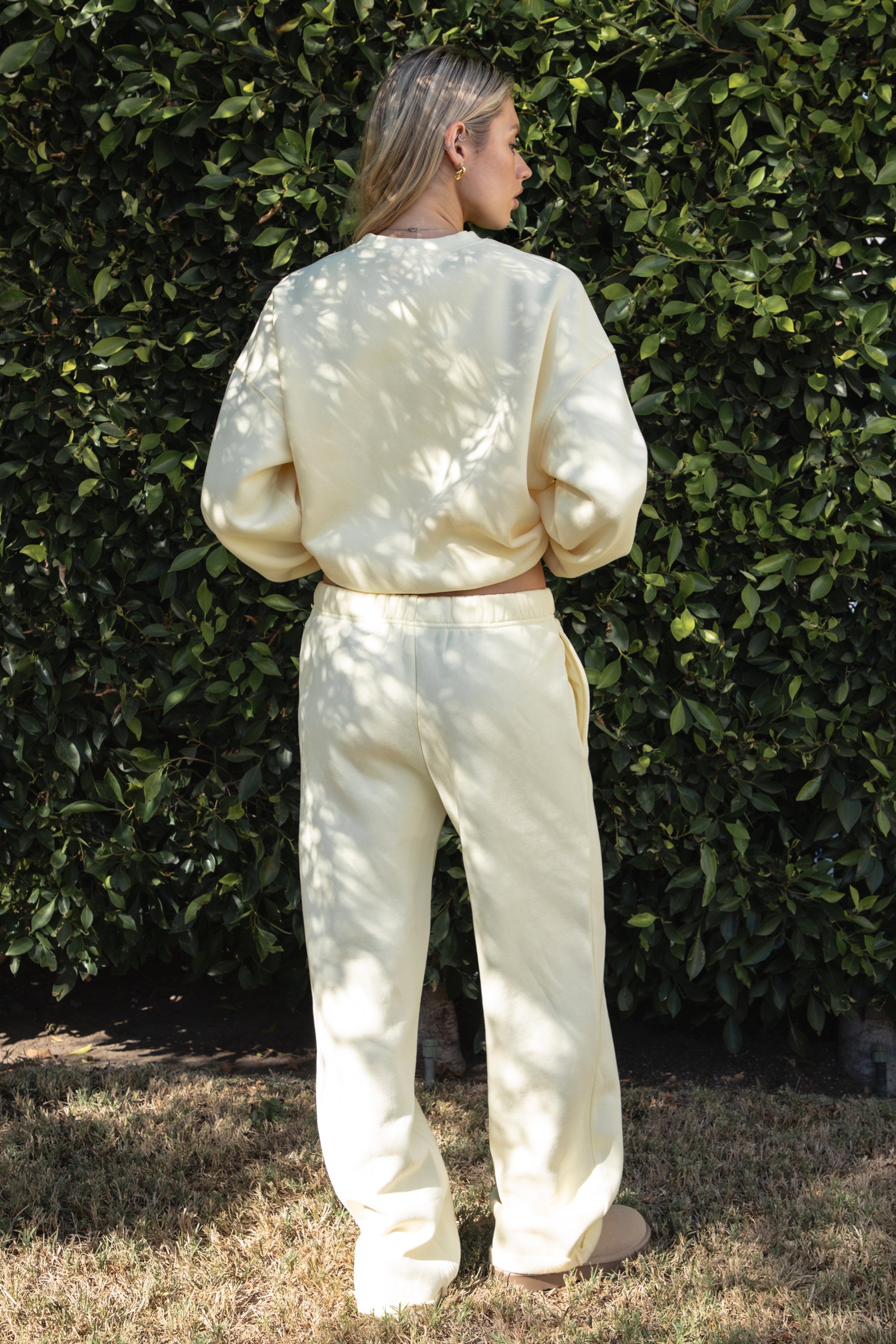 Woman wearing the TIC TOC PJ30241 LANI pale yellow cloud fleece wide leg sweatpants featuring a straight leg silhouette, drawcord waistband, and side pockets paired with a matching sweater. 
