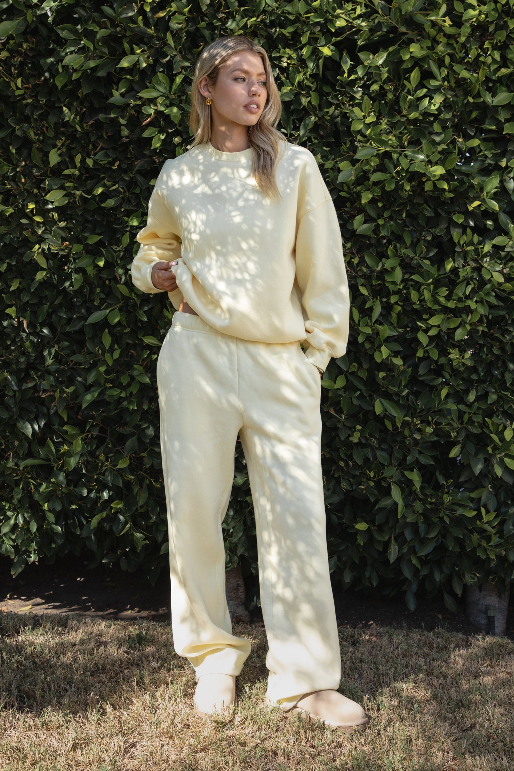 Woman wearing the TIC TOC PJ30241 LANI pale yellow cloud fleece wide leg sweatpants featuring a straight leg silhouette, drawcord waistband, and side pockets paired with a matching sweater. 