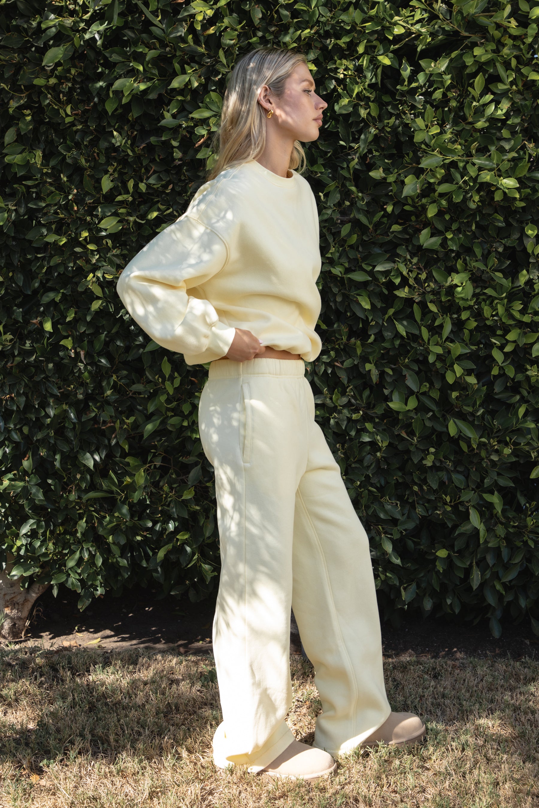 Woman wearing the TIC TOC PJ30241 LANI pale yellow cloud fleece wide leg sweatpants featuring a straight leg silhouette, drawcord waistband, and side pockets paired with a matching sweater. 