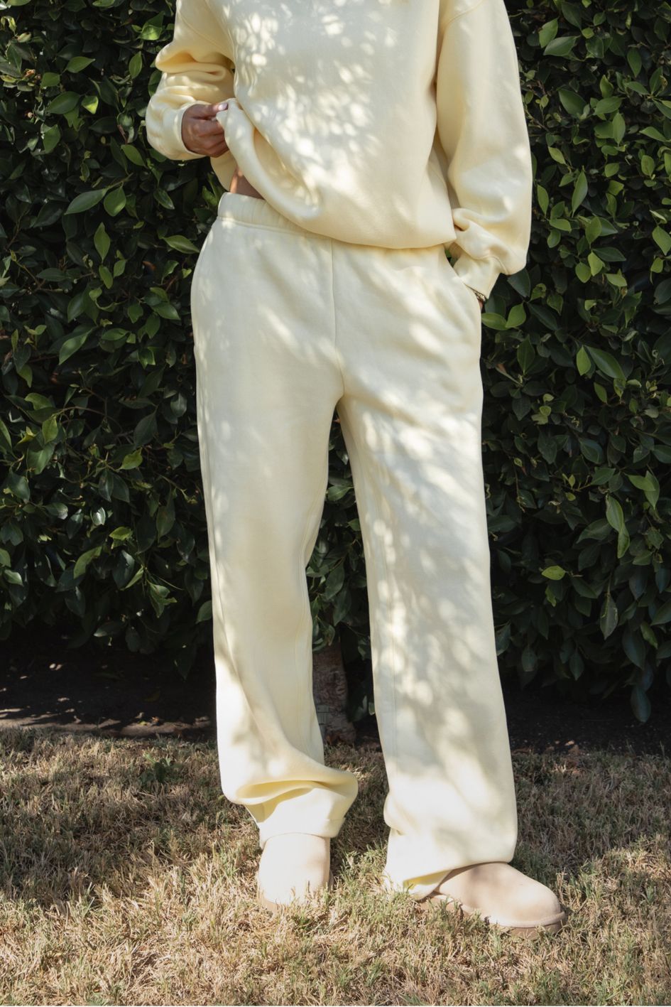 Woman wearing the TIC TOC PJ30241 LANI pale yellow cloud fleece wide leg sweatpants featuring a straight leg silhouette, drawcord waistband, and side pockets paired with a matching sweater. 
