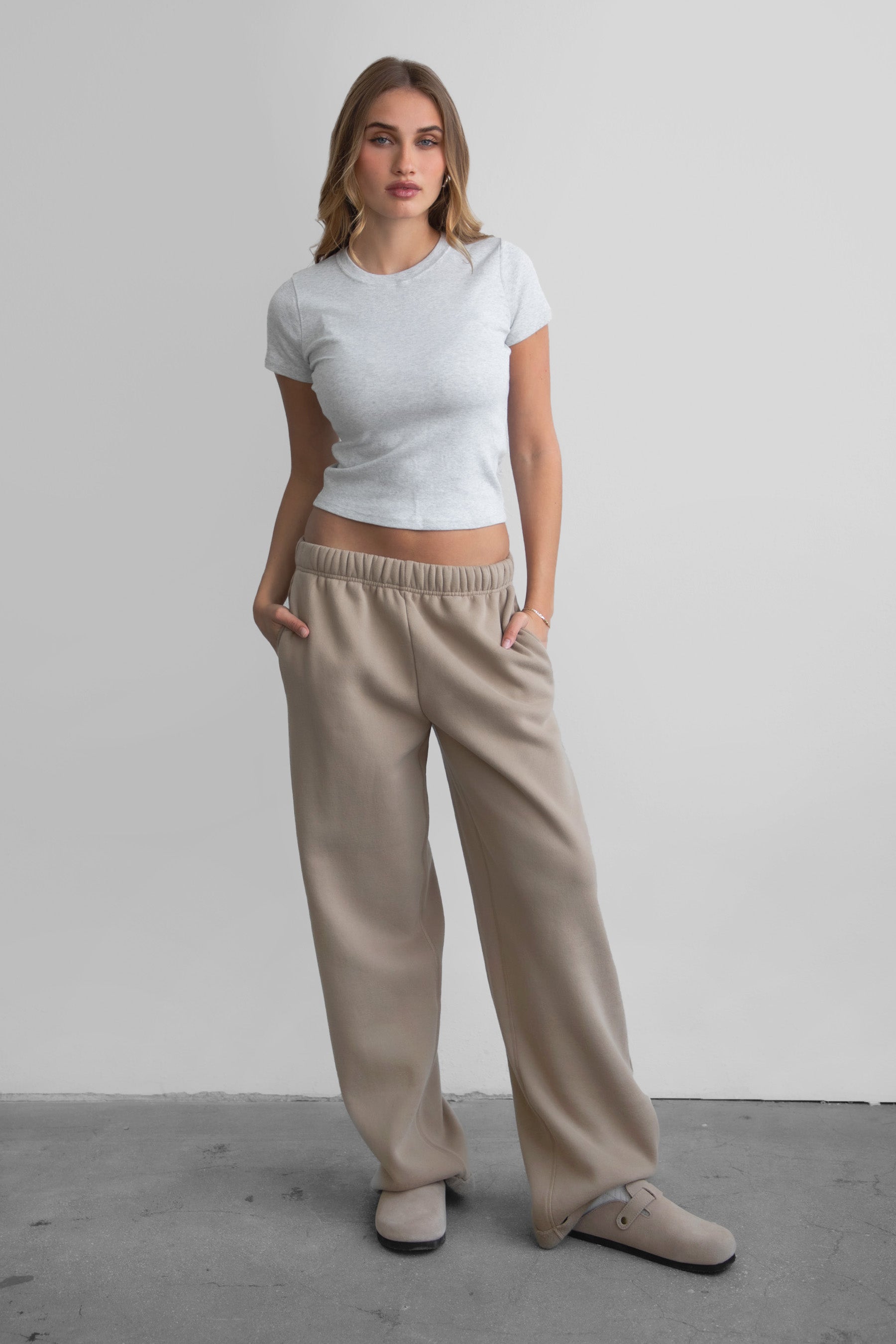 Woman wearing the TIC TOC PJ30241 LANI taupe cloud fleece wide leg sweatpants featuring a straight leg silhouette, drawcord waistband, and side pockets paired with a baby tee. 