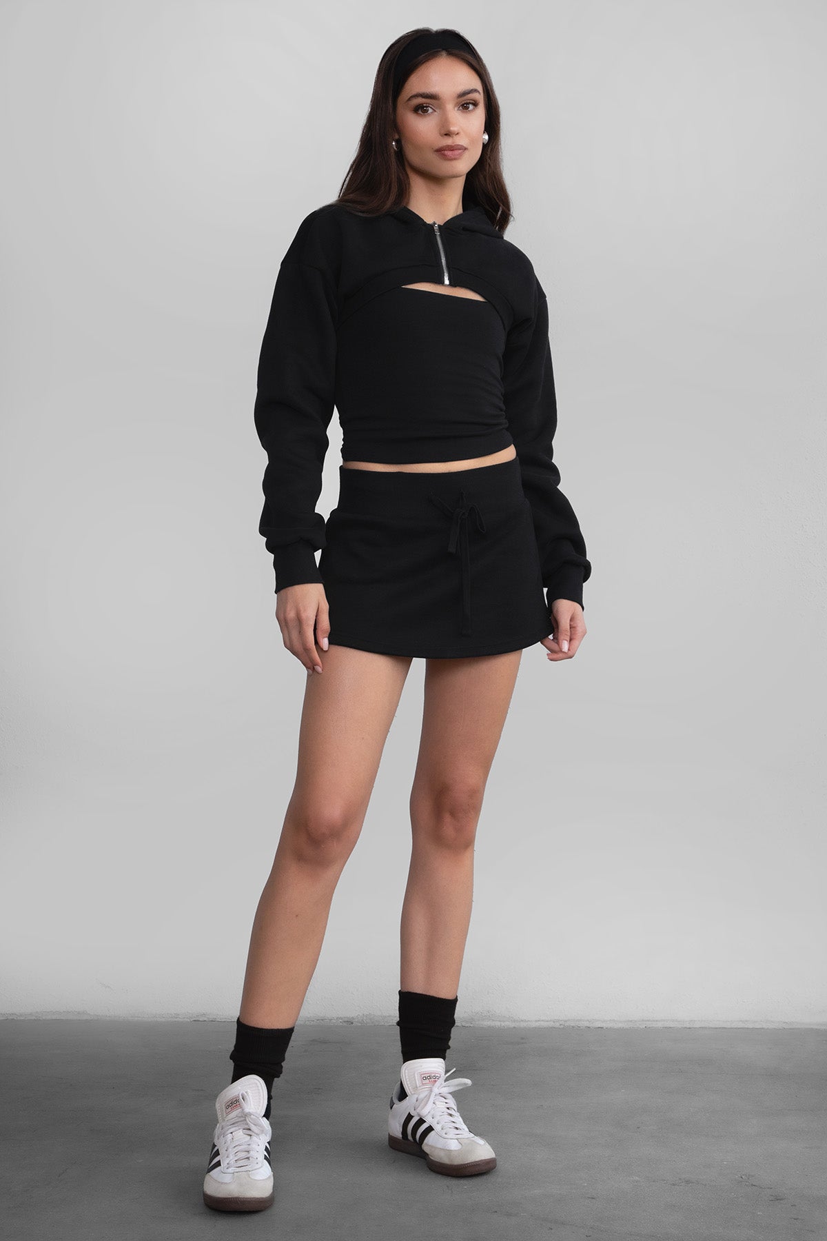 Woman wearing the TIC TOC SH30133BA JEMMA black fleece mini skirt featuring an elastic waistband, drawstring closure, and hidden shorts for comfort and coverage paired with a matching top.