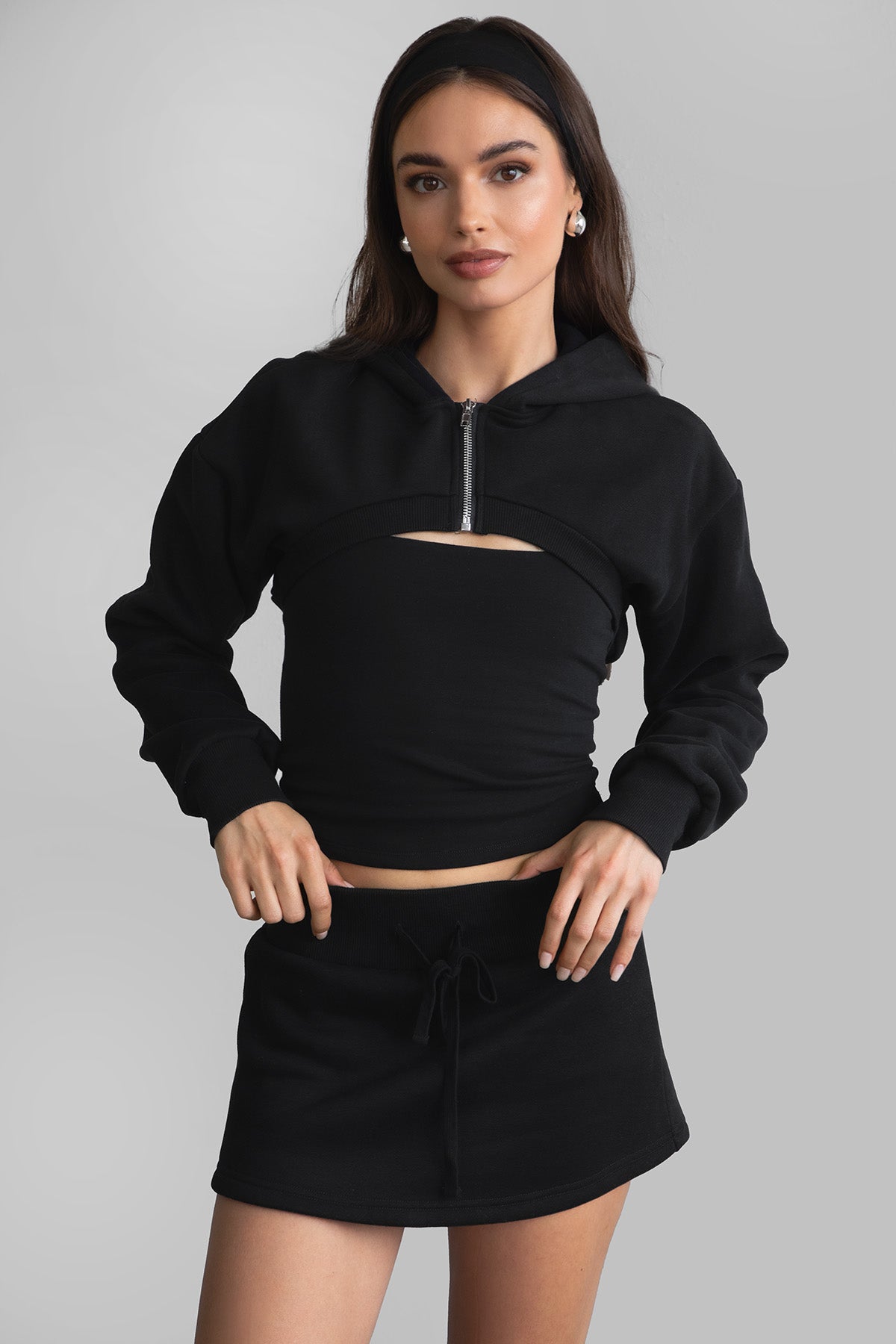 Woman wearing the TIC TOC SH30133BA JEMMA black fleece mini skirt featuring an elastic waistband, drawstring closure, and hidden shorts for comfort and coverage paired with a matching top.