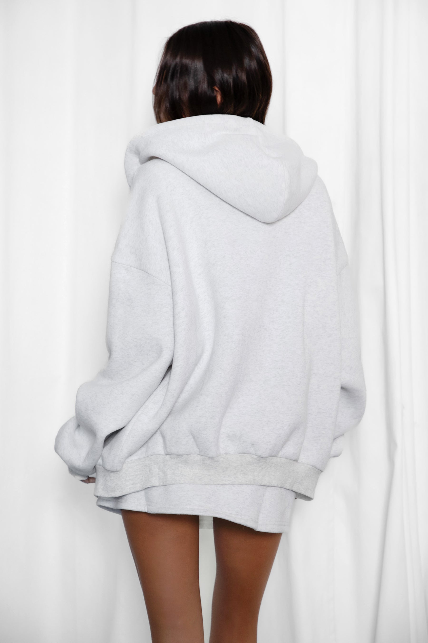 Woman wearing the TIC TOC SH30133BA JEMMA heather white fleece mini skirt featuring an elastic waistband, drawstring closure, and hidden shorts for comfort and coverage paired with a matching top.