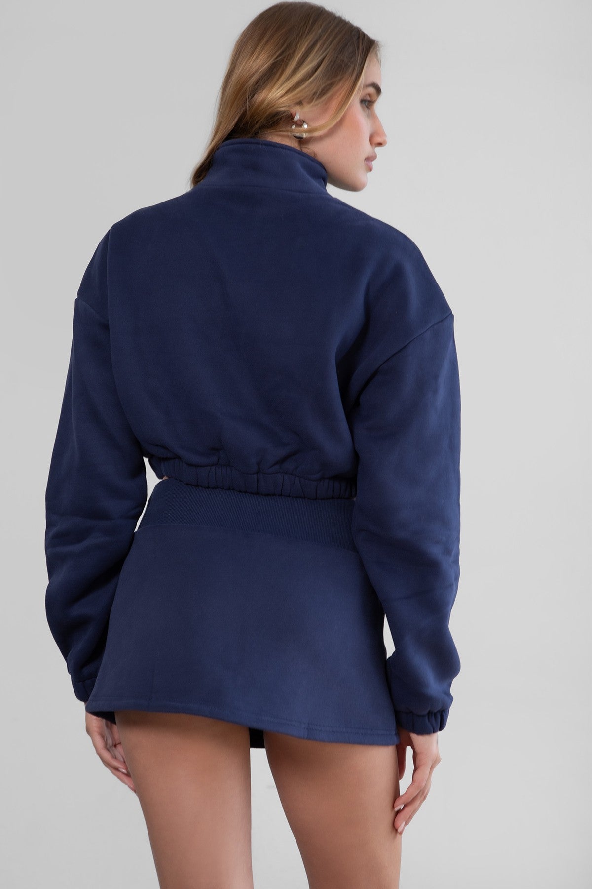 Woman wearing the TIC TOC SH30133BA JEMMA navy fleece mini skirt featuring an elastic waistband, drawstring closure, and hidden shorts for comfort and coverage paired with a matching top.