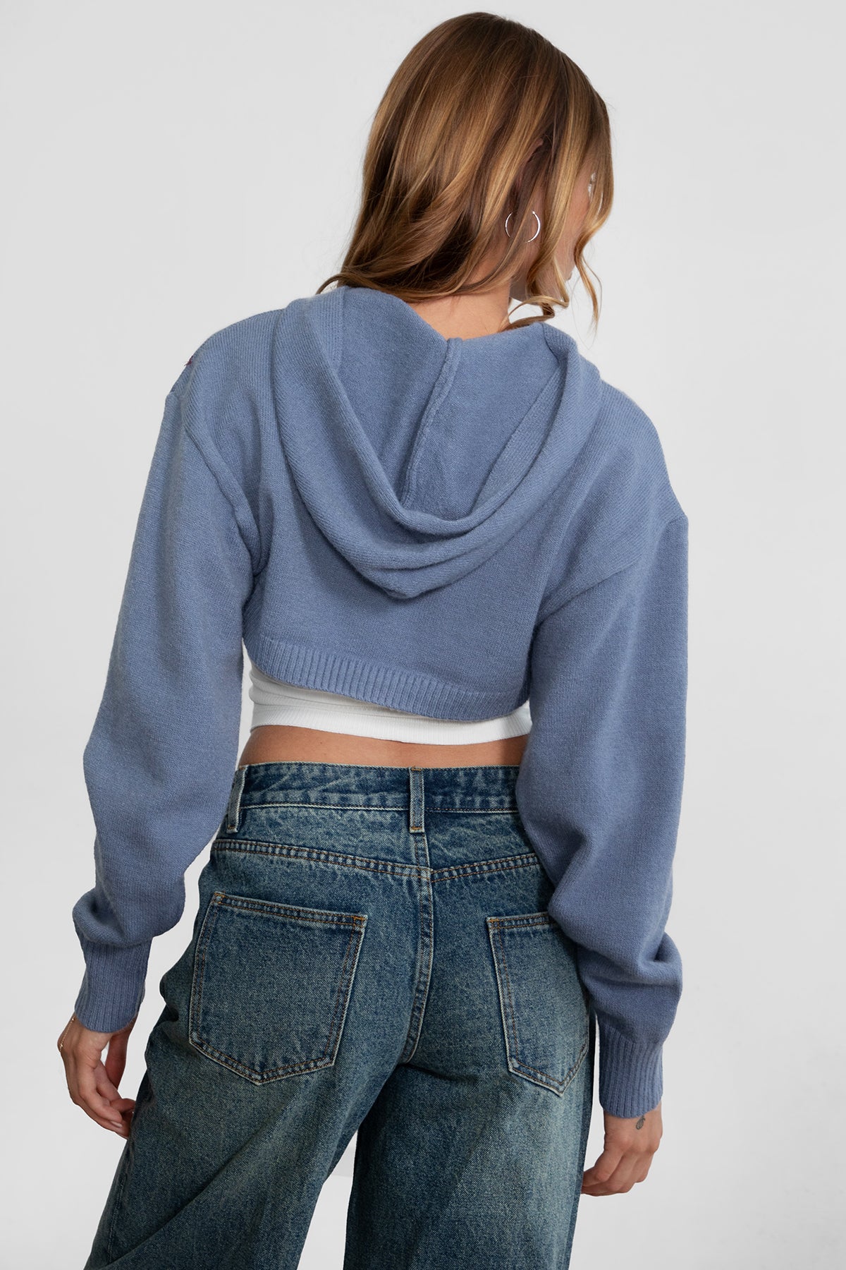 Woman wearing TIC TOC TC29152 FREYA ultra cropped hooded cardigan with ribbed knit fabric and double ended zipper in french blue