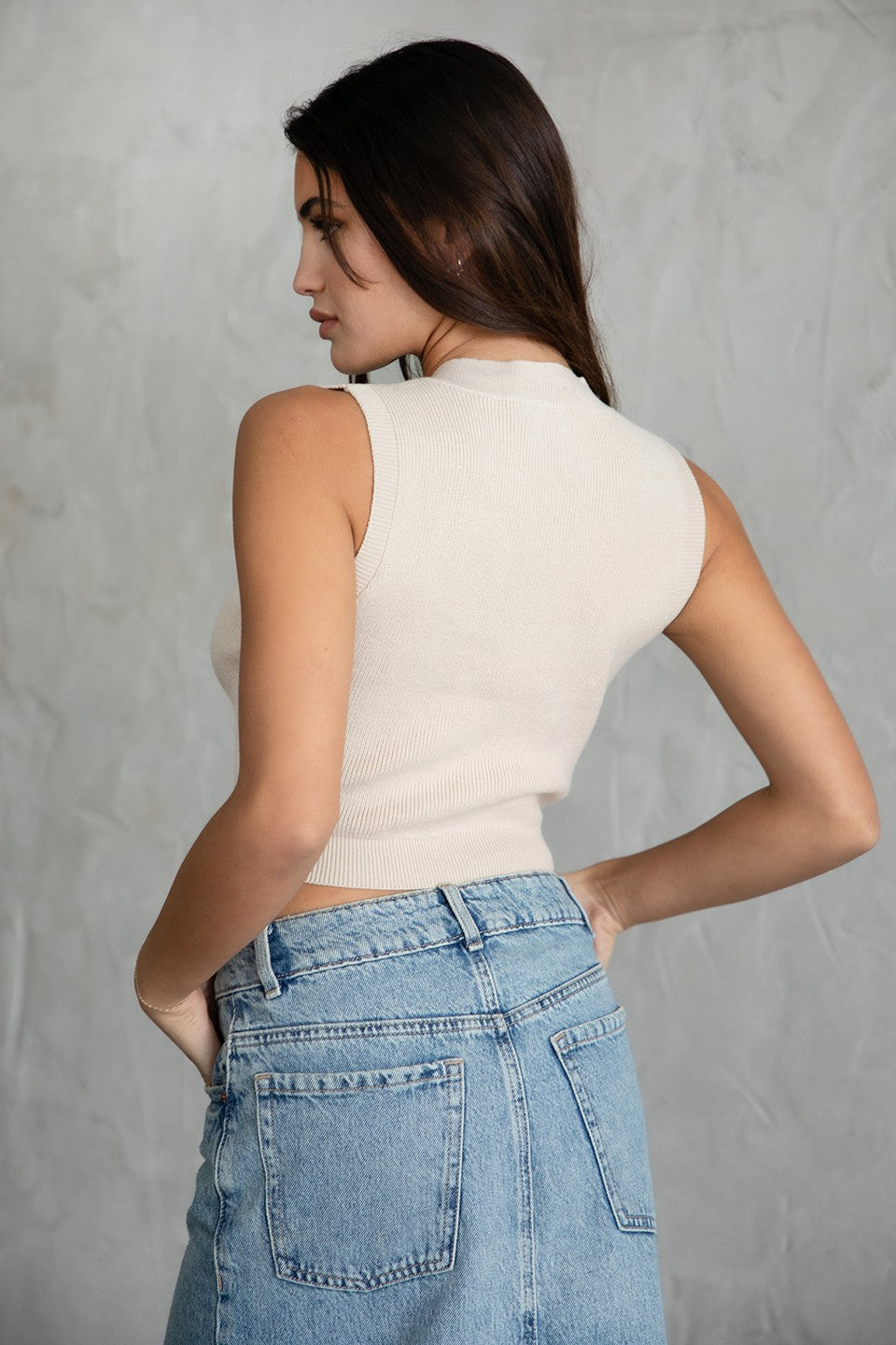 Woman wearing TIC TOC TC29860 KELLIE ribbed knit sweater vest with v neckline and slim hip length fit in color khaki, paired with denim bottoms. 