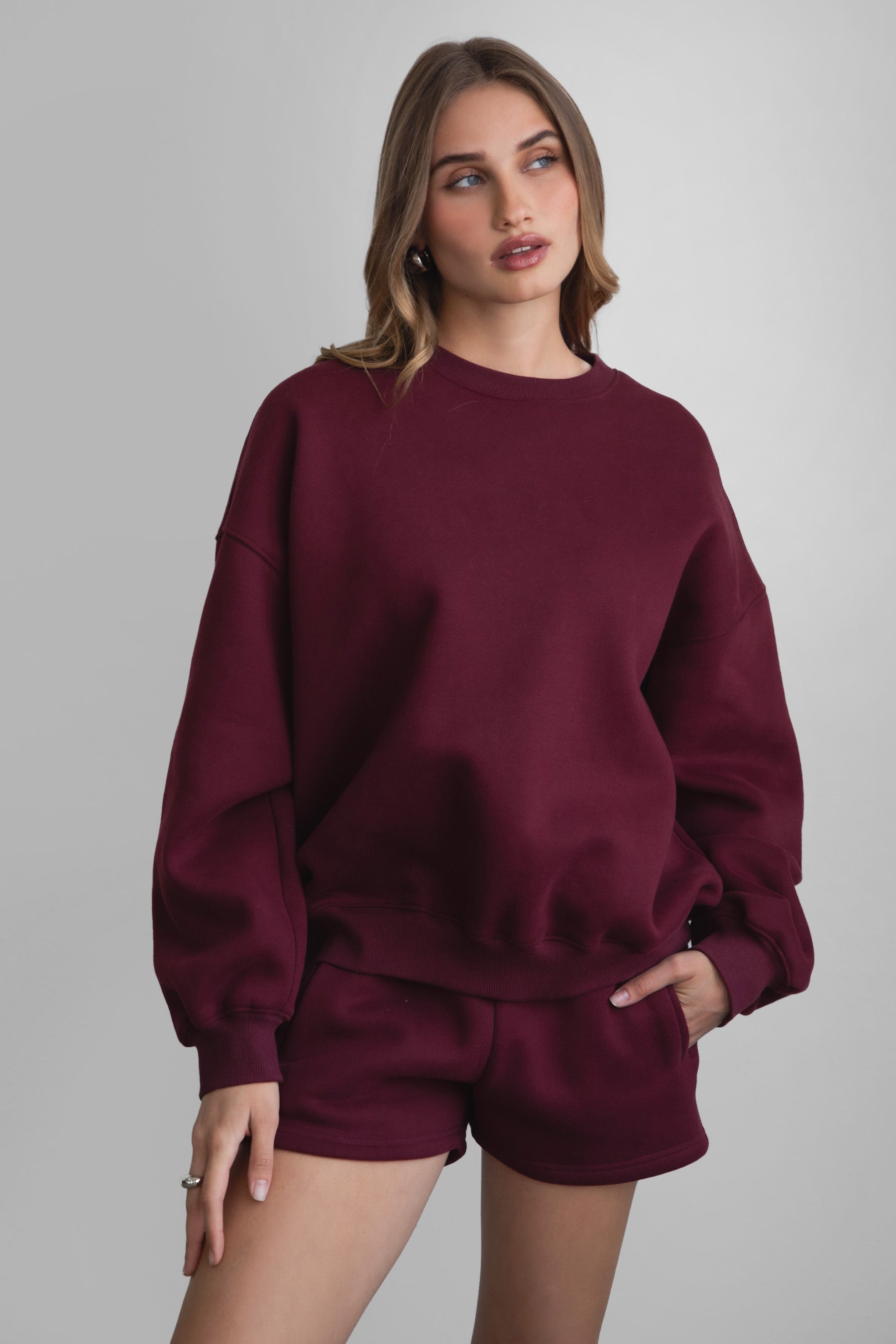 Woman wearing the TIC TOC TH28243 VARSITY black cherry fleece crew neck pullover sweatshirt featuring dropped shoulders, ribbed trim, and plush fleece fabric with the matching bottoms 