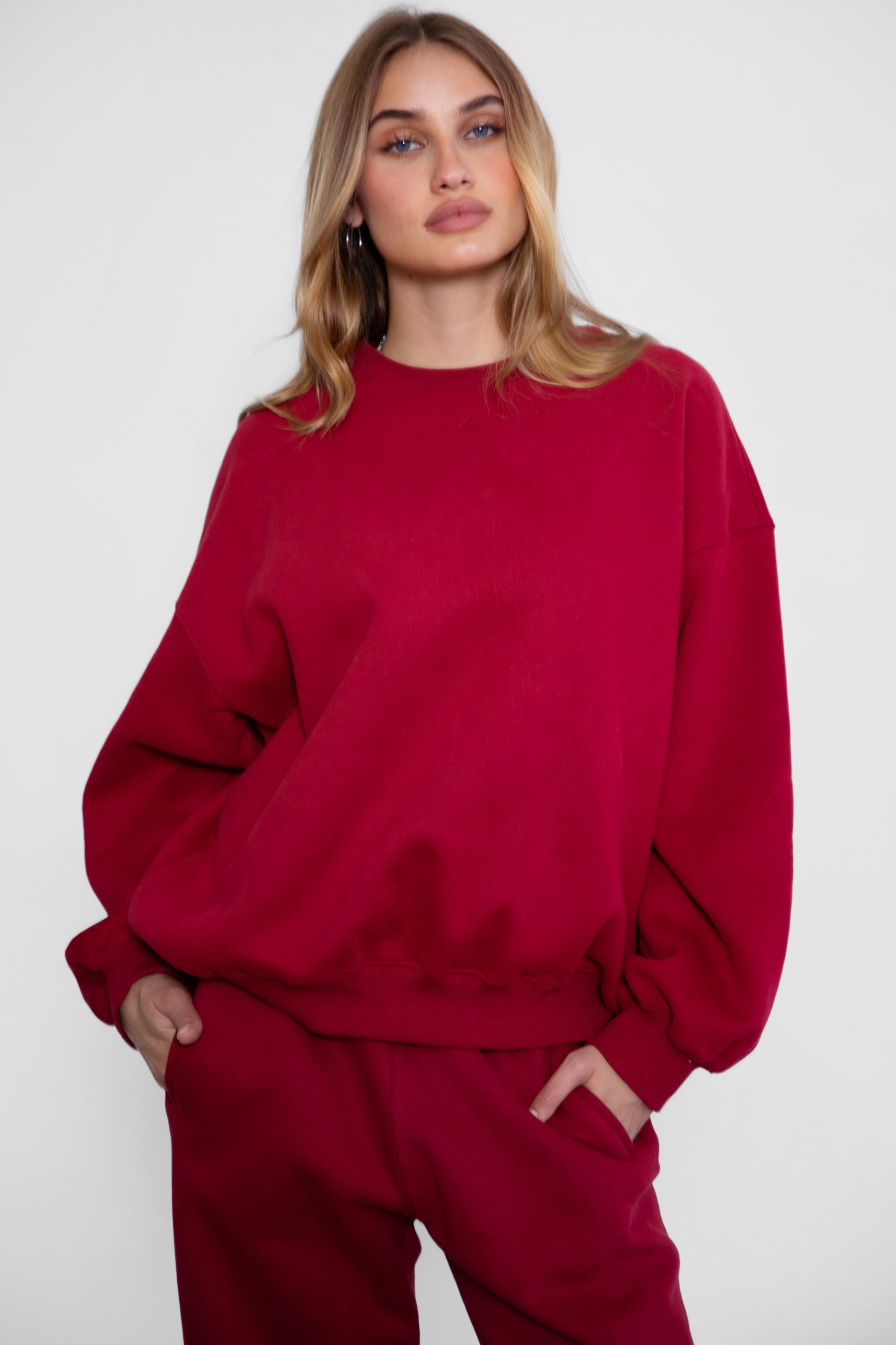 Woman wearing the TIC TOC TH28243 VARSITY burgundy fleece crew neck pullover sweatshirt featuring dropped shoulders, ribbed trim, and plush fleece fabric with the matching bottoms 