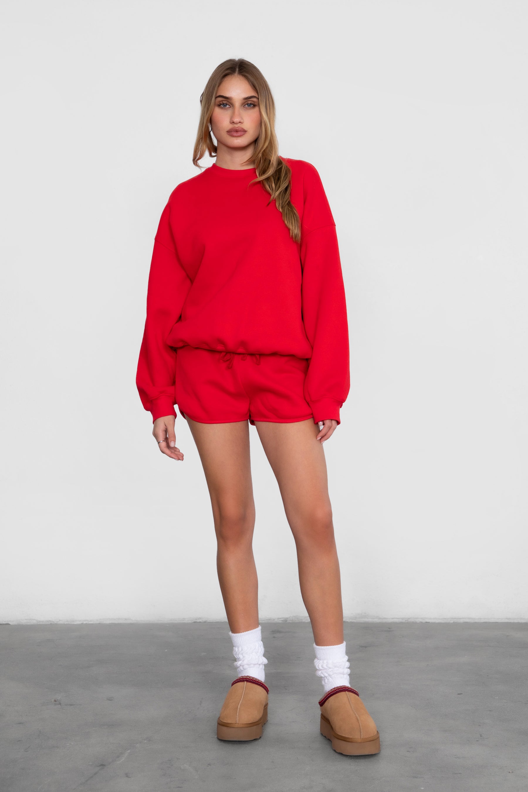 Woman wearing the TIC TOC TH28243 VARSITY cherry red fleece crew neck pullover sweatshirt featuring dropped shoulders, ribbed trim, and plush fleece fabric with the matching bottoms 