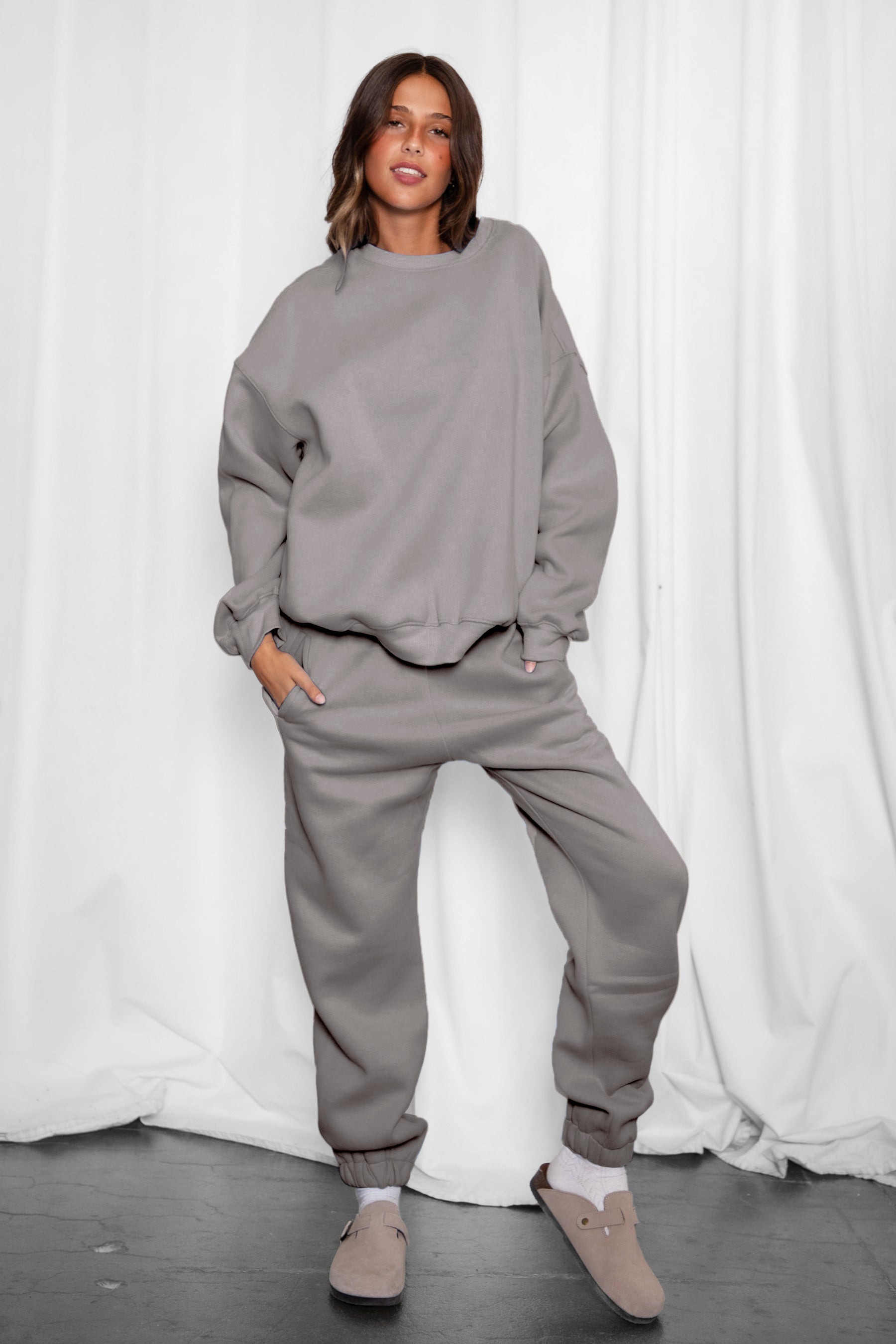 Woman wearing the TIC TOC TH28243 VARSITY grey fleece crew neck pullover sweatshirt featuring dropped shoulders, ribbed trim, and plush fleece fabric with the matching bottoms 