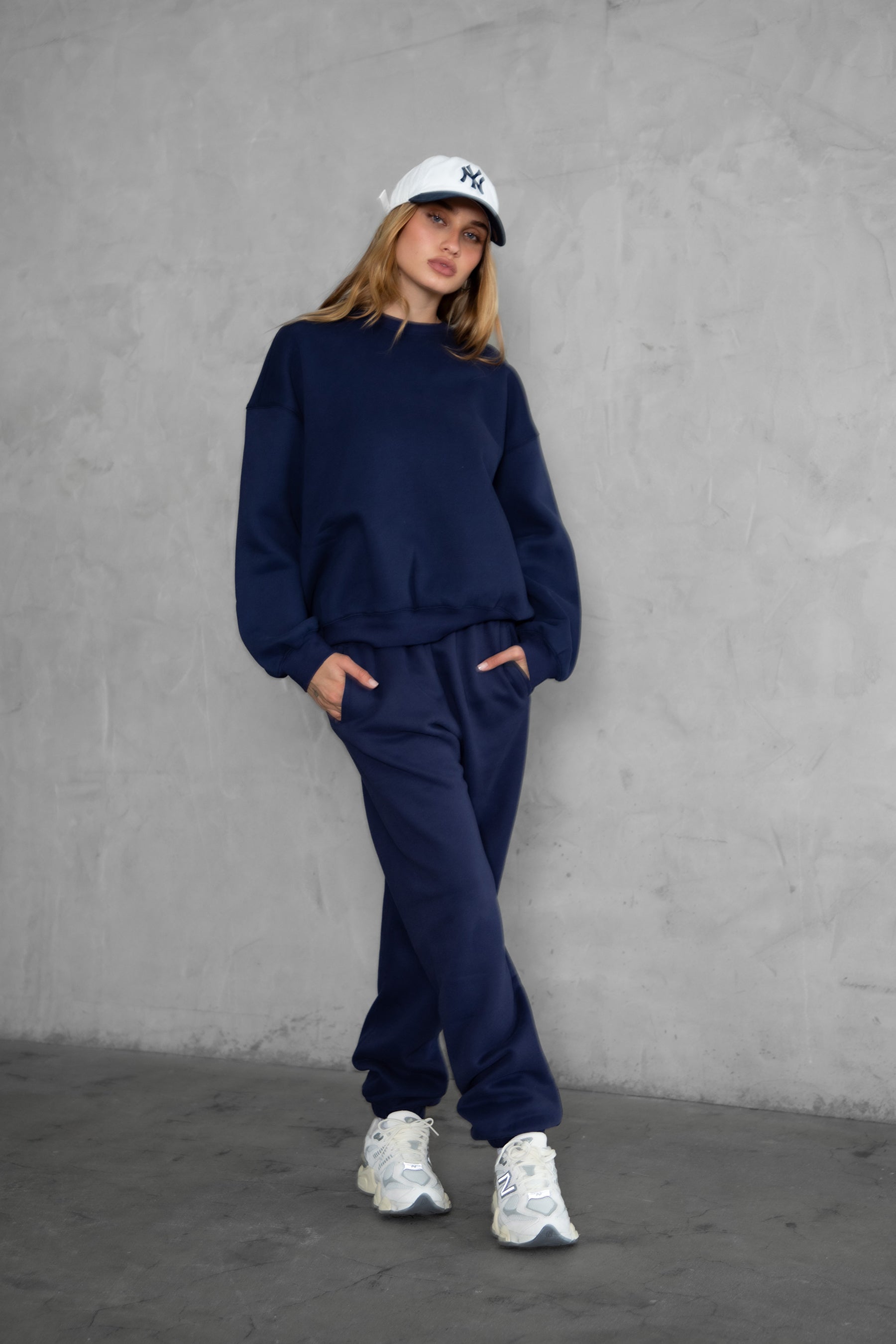 Woman wearing the TIC TOC TH28243 VARSITY navy blue fleece crew neck pullover sweatshirt featuring dropped shoulders, ribbed trim, and plush fleece fabric with the matching bottoms 