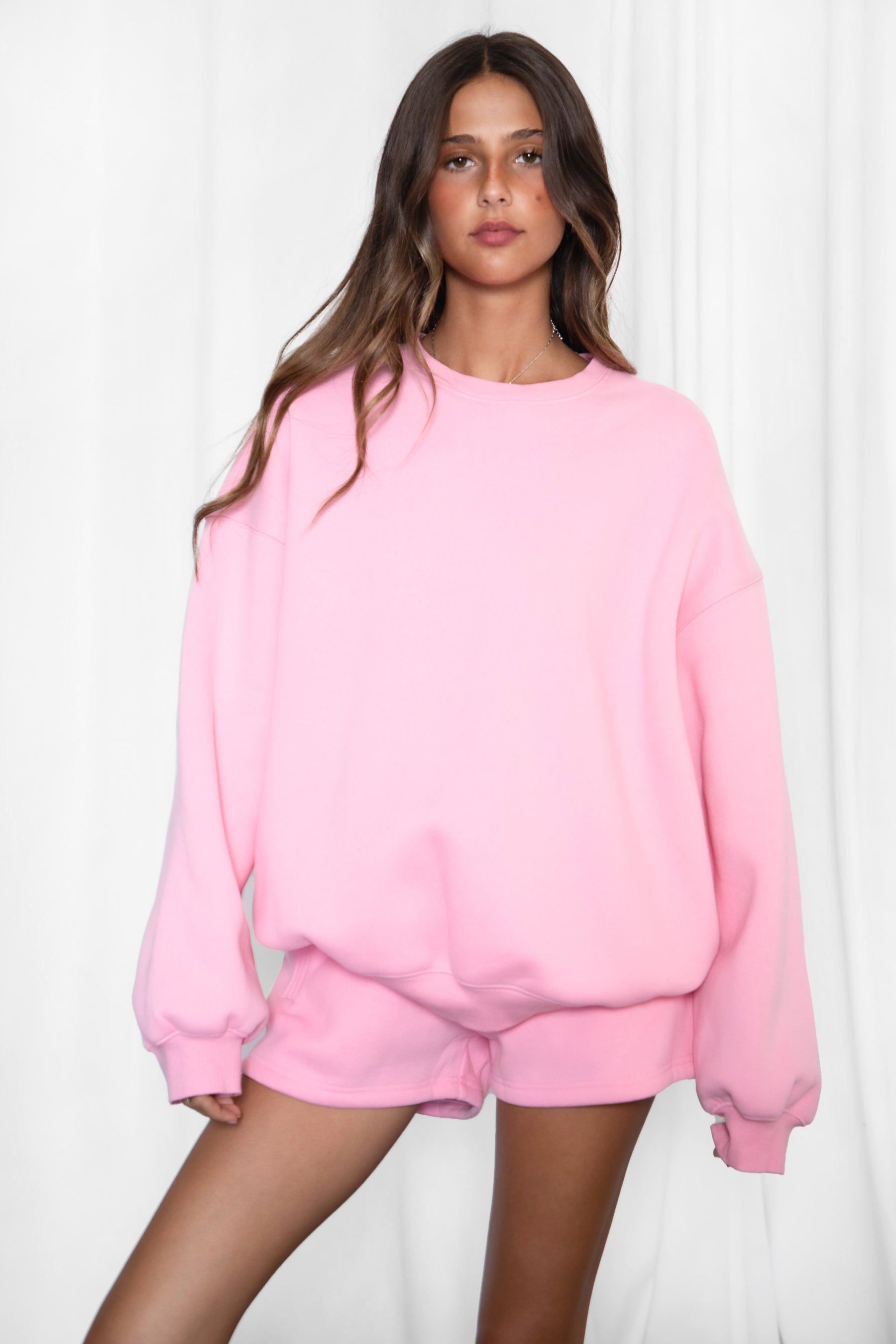 Woman wearing the TIC TOC TH28243 VARSITY pink fleece crew neck pullover sweatshirt featuring dropped shoulders, ribbed trim, and plush fleece fabric with the matching bottoms 