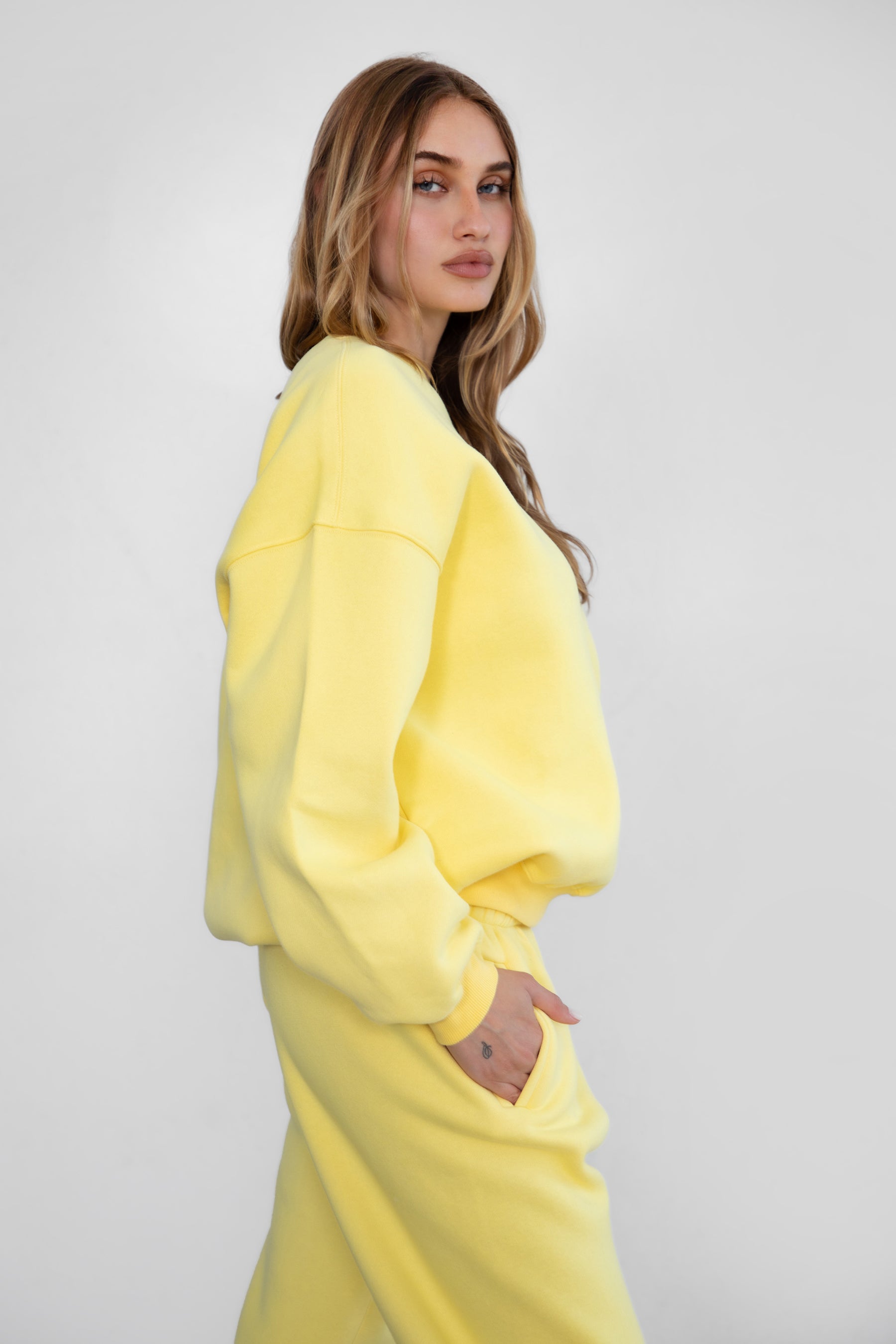 Woman wearing the TIC TOC TH28243 VARSITY yellow fleece crew neck pullover sweatshirt featuring dropped shoulders, ribbed trim, and plush fleece fabric with the matching bottoms 