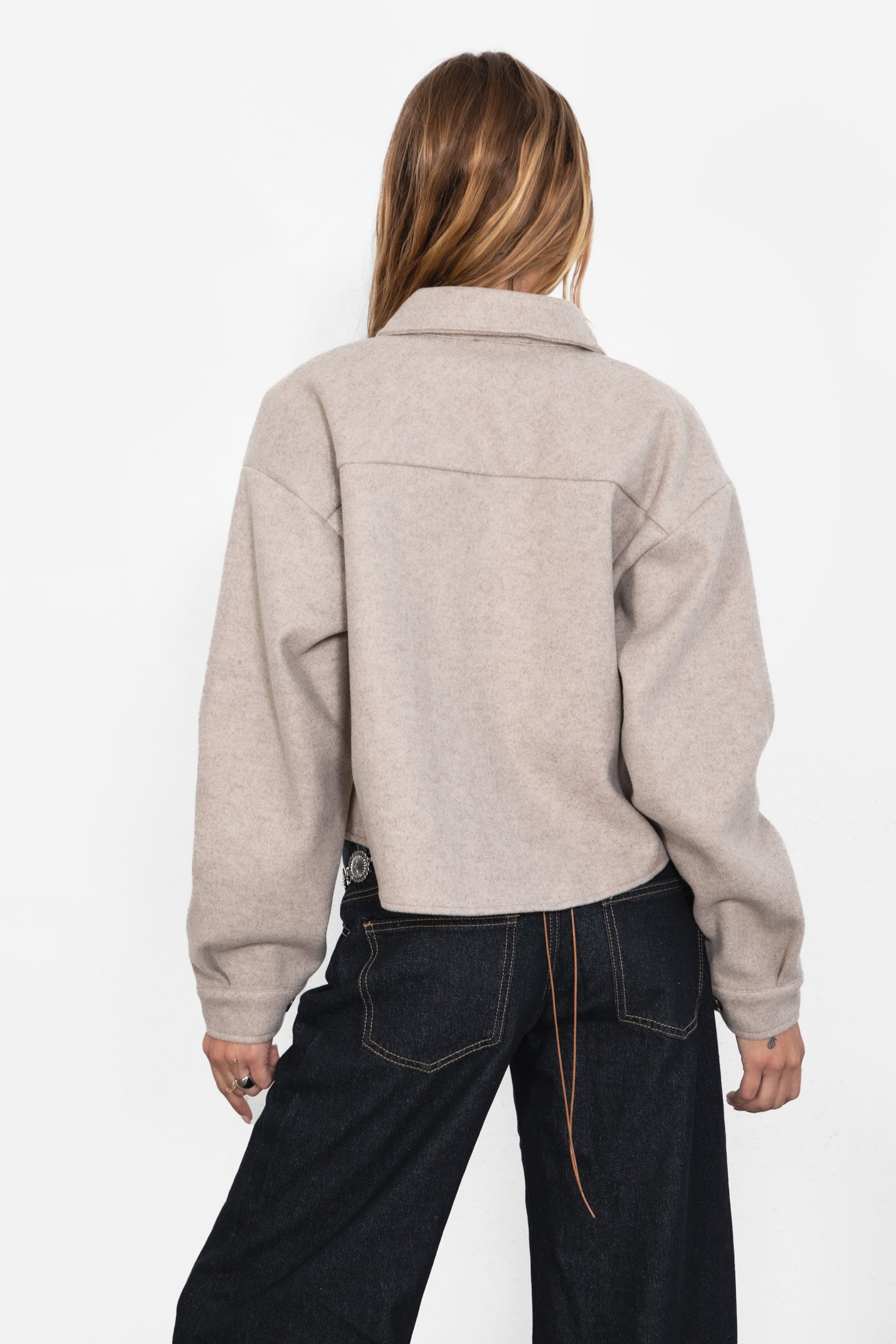 Woman wearing TIC TOC TH29147 WOOLIE faux wool cropped shacket with button front, collared neckline, and double pocket detail in color taupe paired with dark denim pants. 
