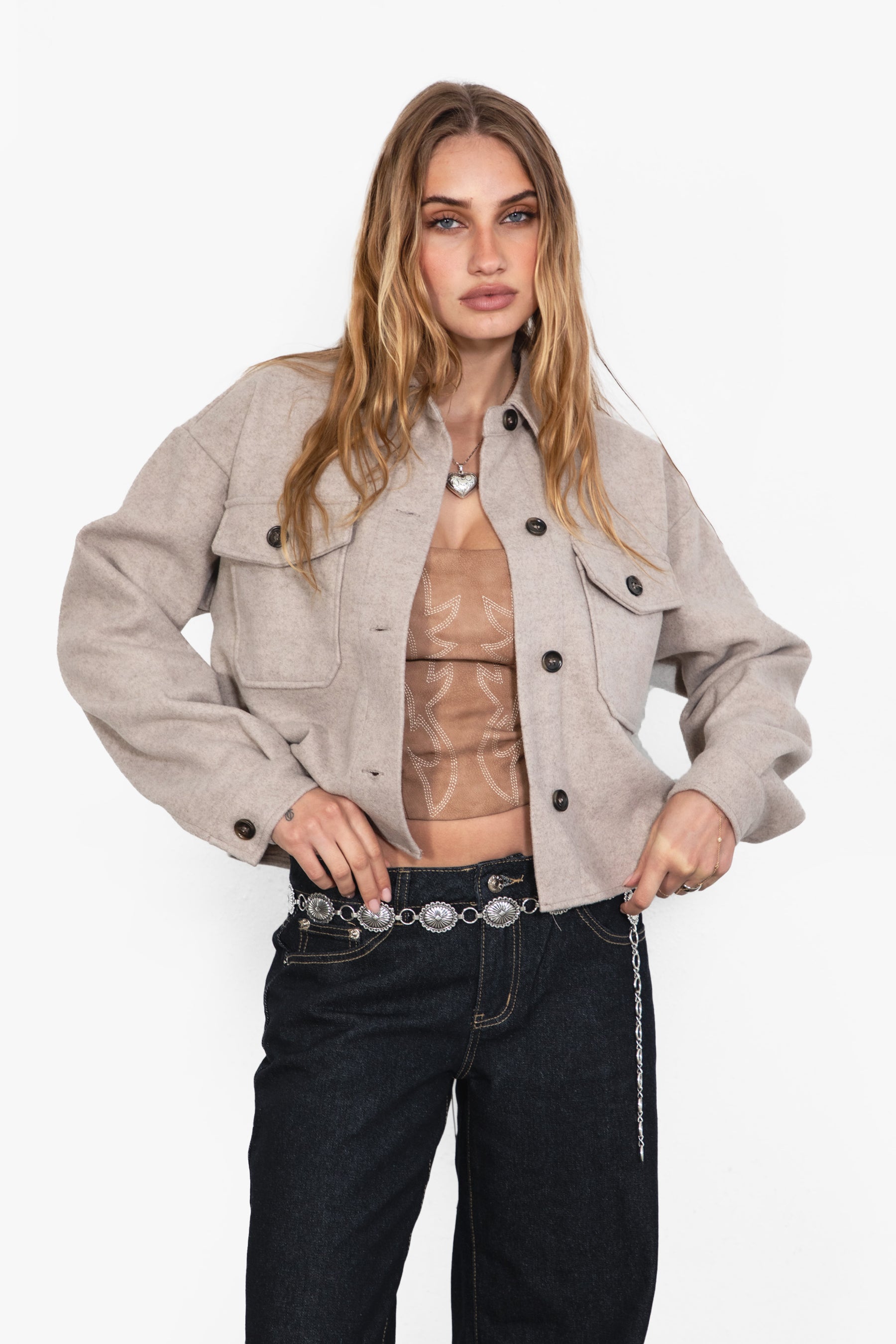 Woman wearing TIC TOC TH29147 WOOLIE faux wool cropped shacket with button front, collared neckline, and double pocket detail in color taupe paired with dark denim pants. 
