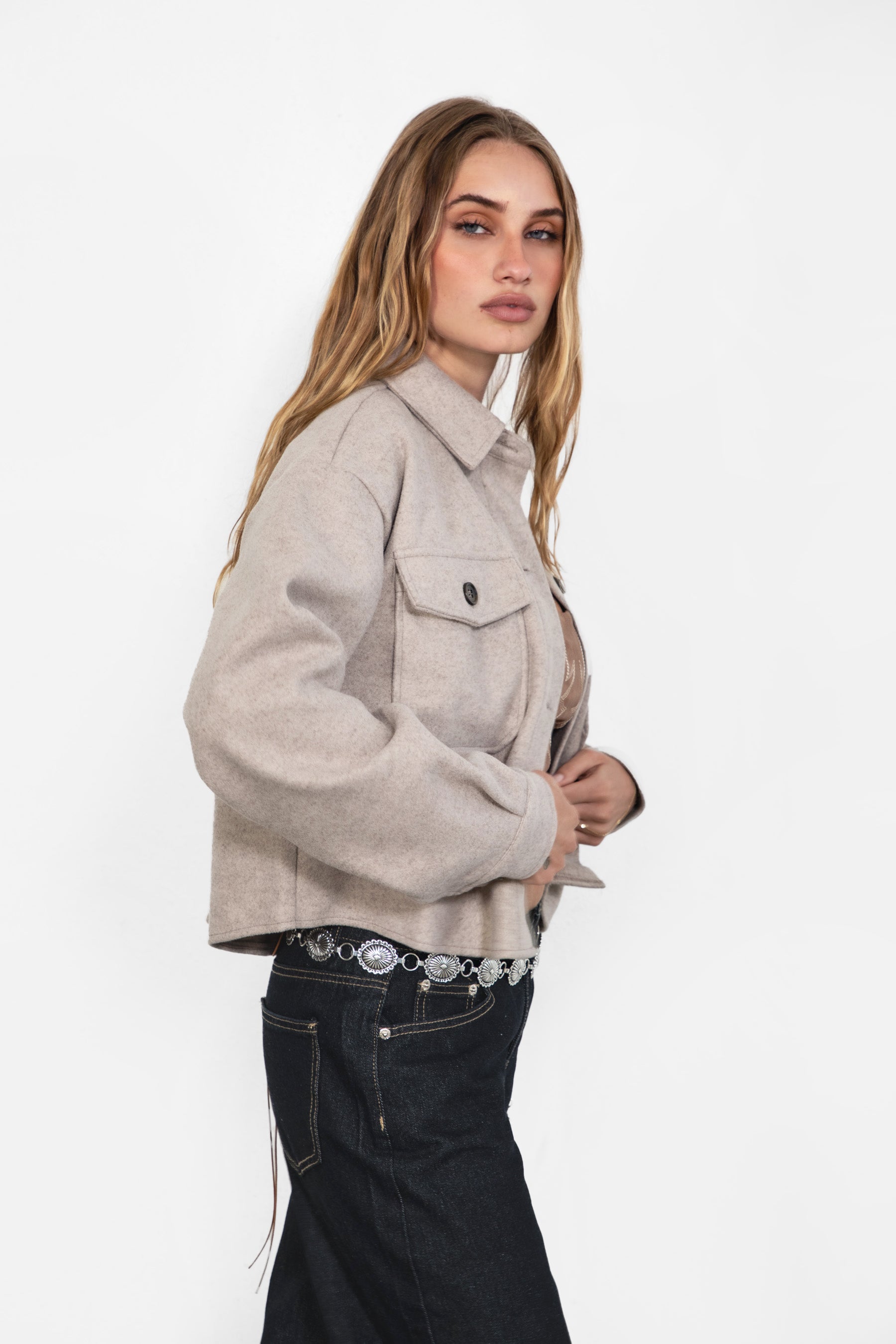 Woman wearing TIC TOC TH29147 WOOLIE faux wool cropped shacket with button front, collared neckline, and double pocket detail in color taupe paired with dark denim pants. 
