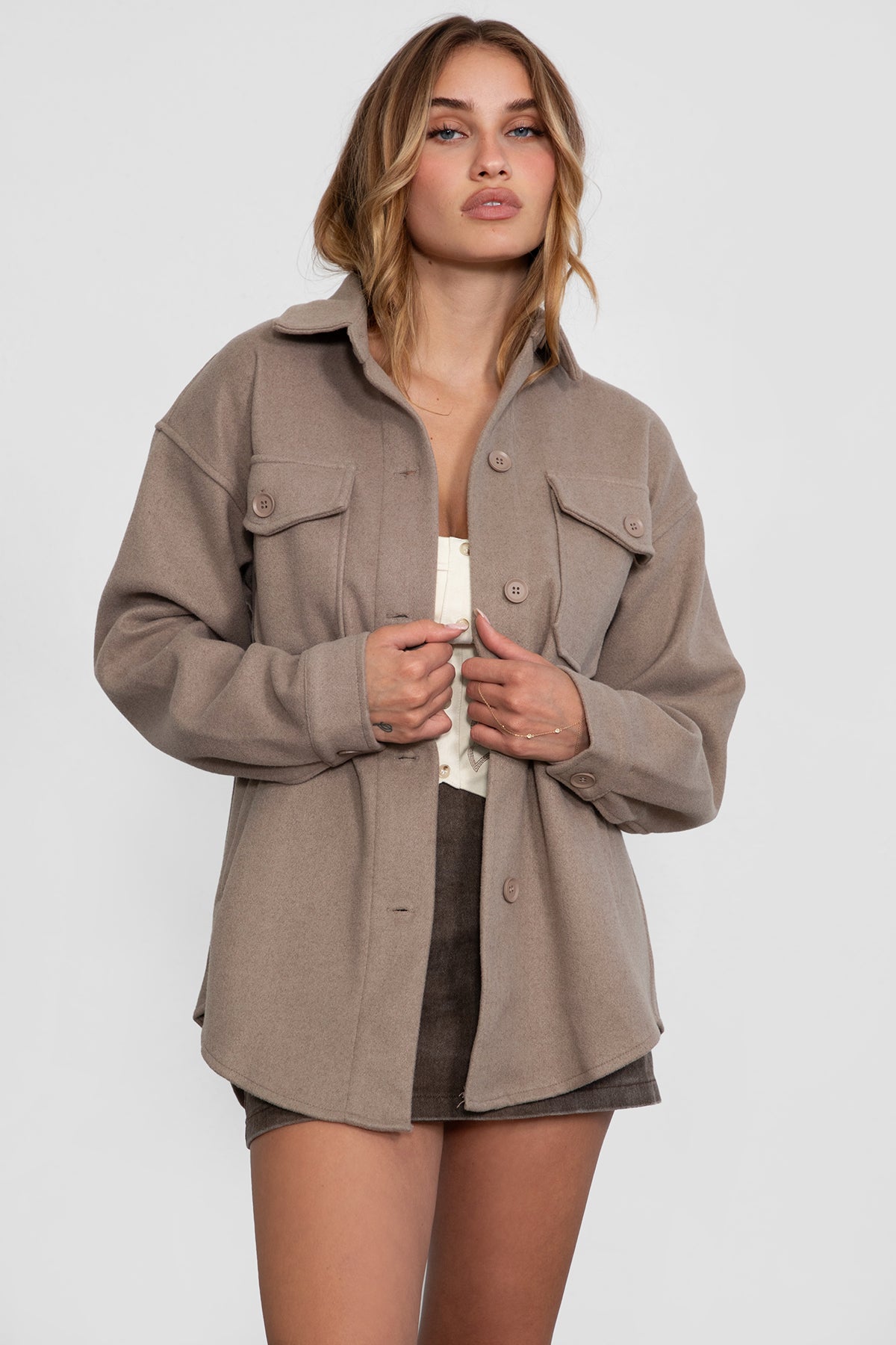 Woman wearing TIC TOC TH29148 BIRKEN faux wool oversized shirt shacket with button front and double pockets in color taupe paired with a brown mini skirt
