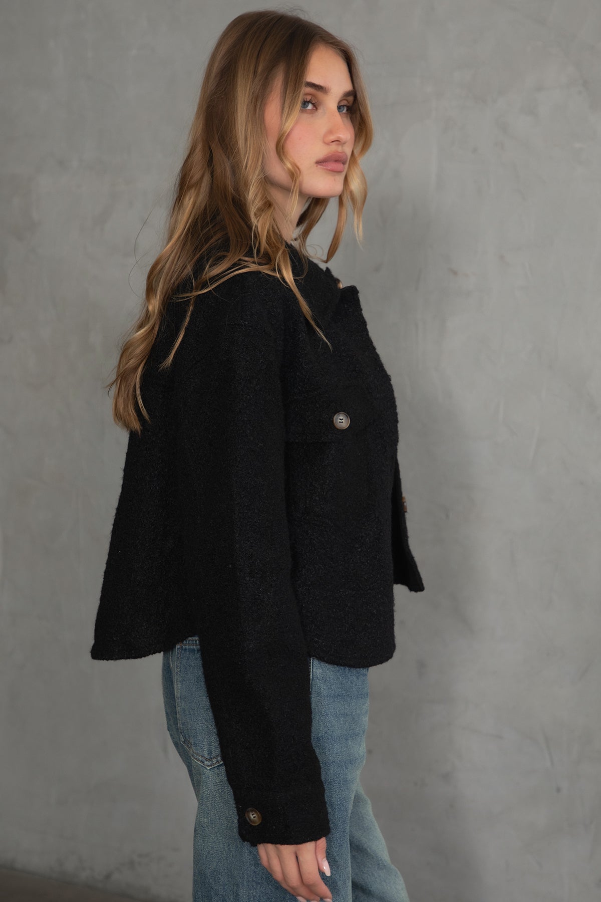 Woman wearing TIC TOC TH29288 FRAY faux sherpa cropped shacket with button front, double pockets, and collared neckline in color black paired with denim jeans