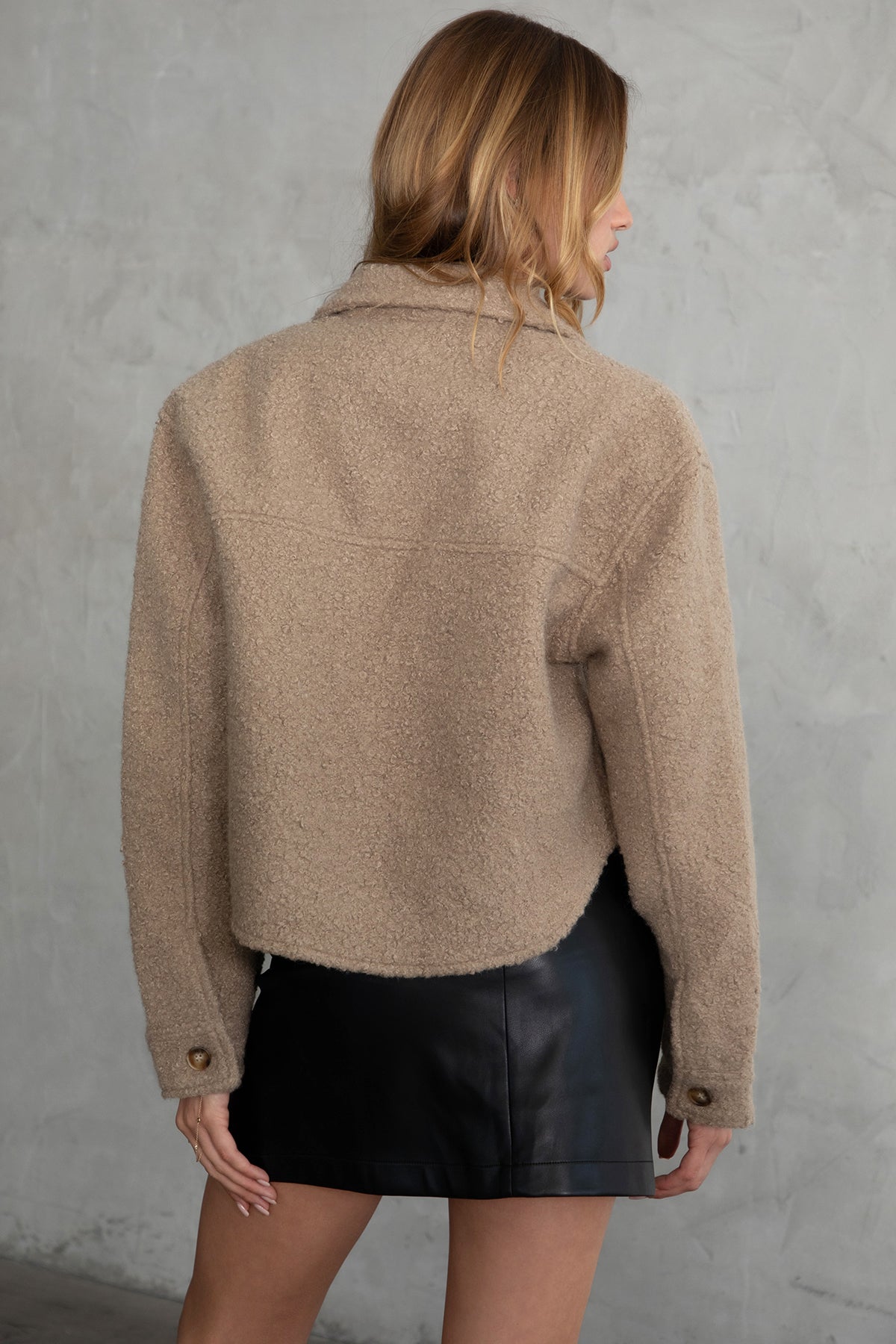 Woman wearing TIC TOC TH29288 FRAY faux sherpa cropped shacket with button front, double pockets, and collared neckline in color taupe paired with a black mini skirt 
