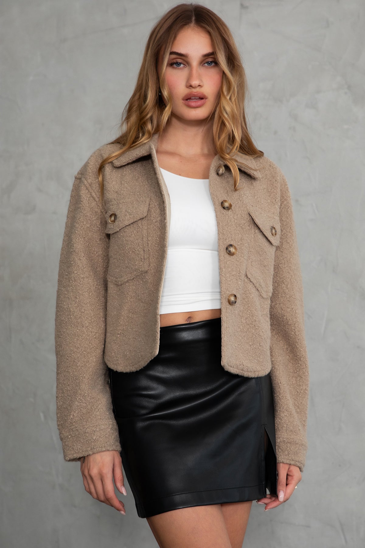 Woman wearing TIC TOC TH29288 FRAY faux sherpa cropped shacket with button front, double pockets, and collared neckline in color taupe paired with a black mini skirt 
