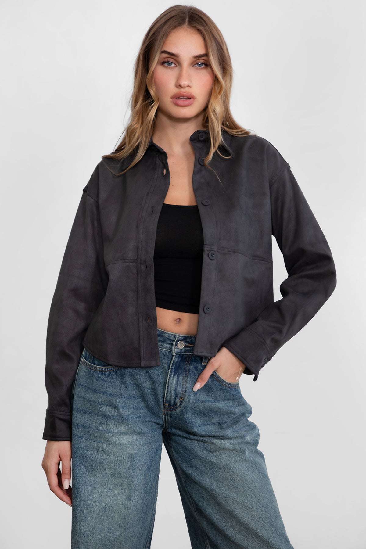 Woman wearing TIC TOC TH29341 LORIA faux suede cropped shacket with collared neckline and button front design inc harcoal paired with denim jeans. 