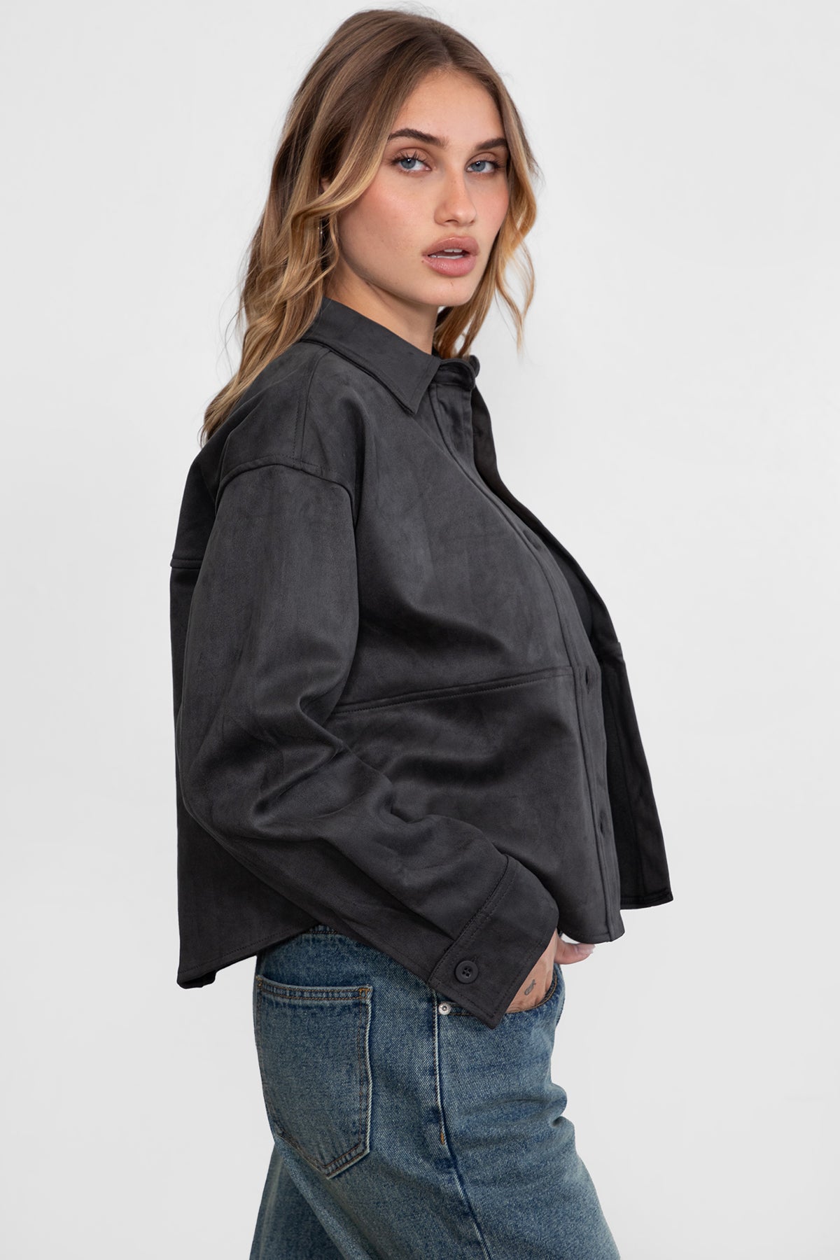 Woman wearing TIC TOC TH29341 LORIA faux suede cropped shacket with collared neckline and button front design inc harcoal paired with denim jeans. 