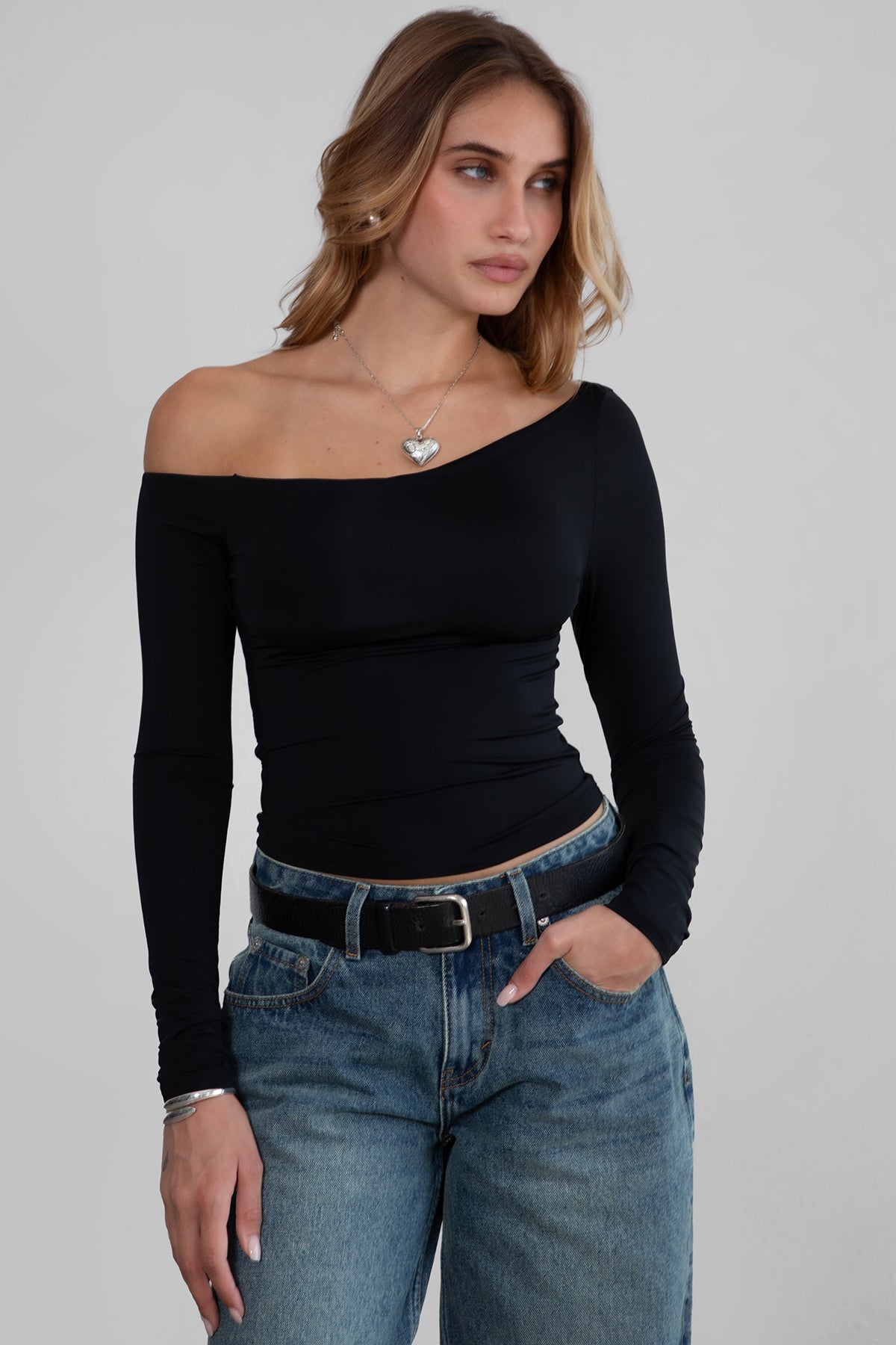 Woman wearing TIC TOC TH30538 AUDREE lightweight one-shoulder long sleeve top in slim fit stretch fabric in color black paired with dark denim blue jeans. 