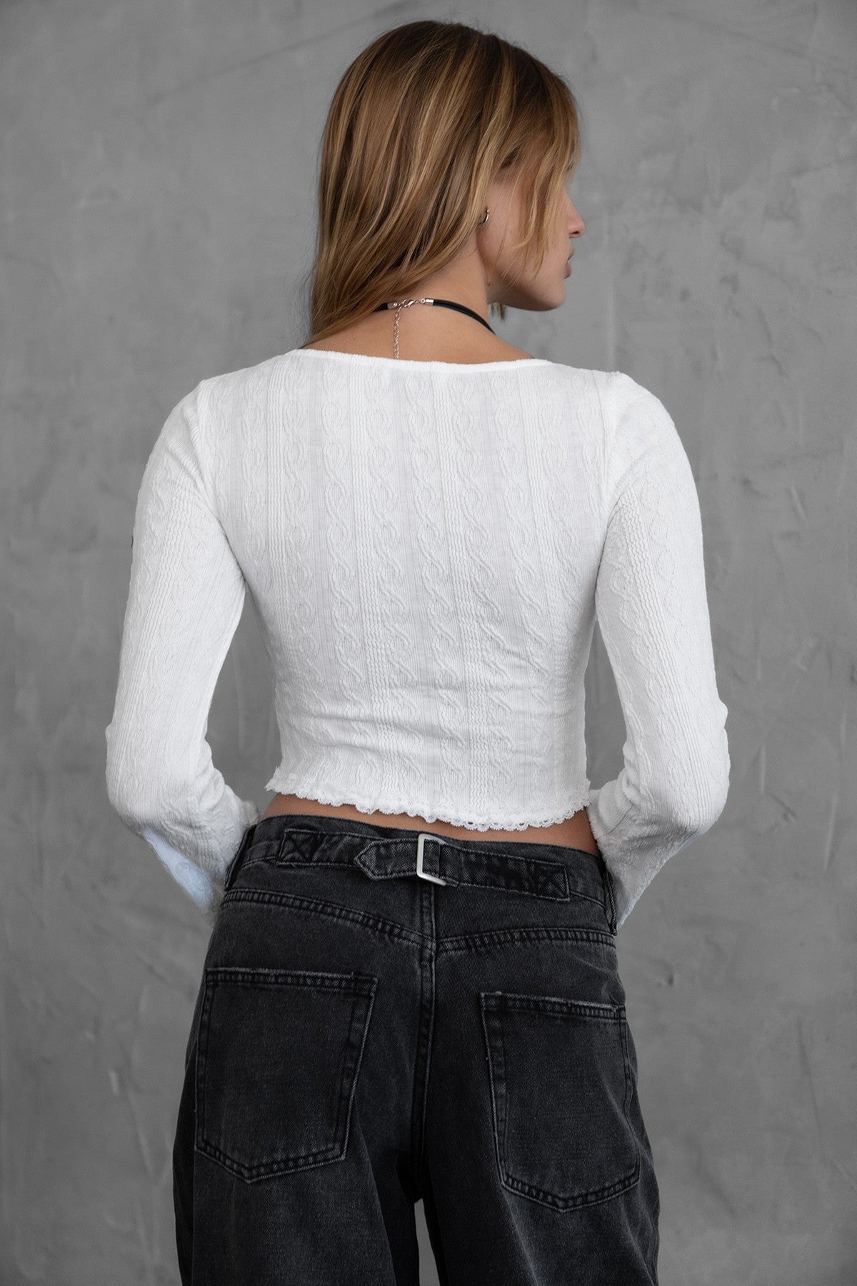 oman wearing TIC TOC TH30540 MARYLYN lacey long sleeve cropped top with scoop neckline, ruched tie, and lace trim hem in color white paired with black denim pants. 